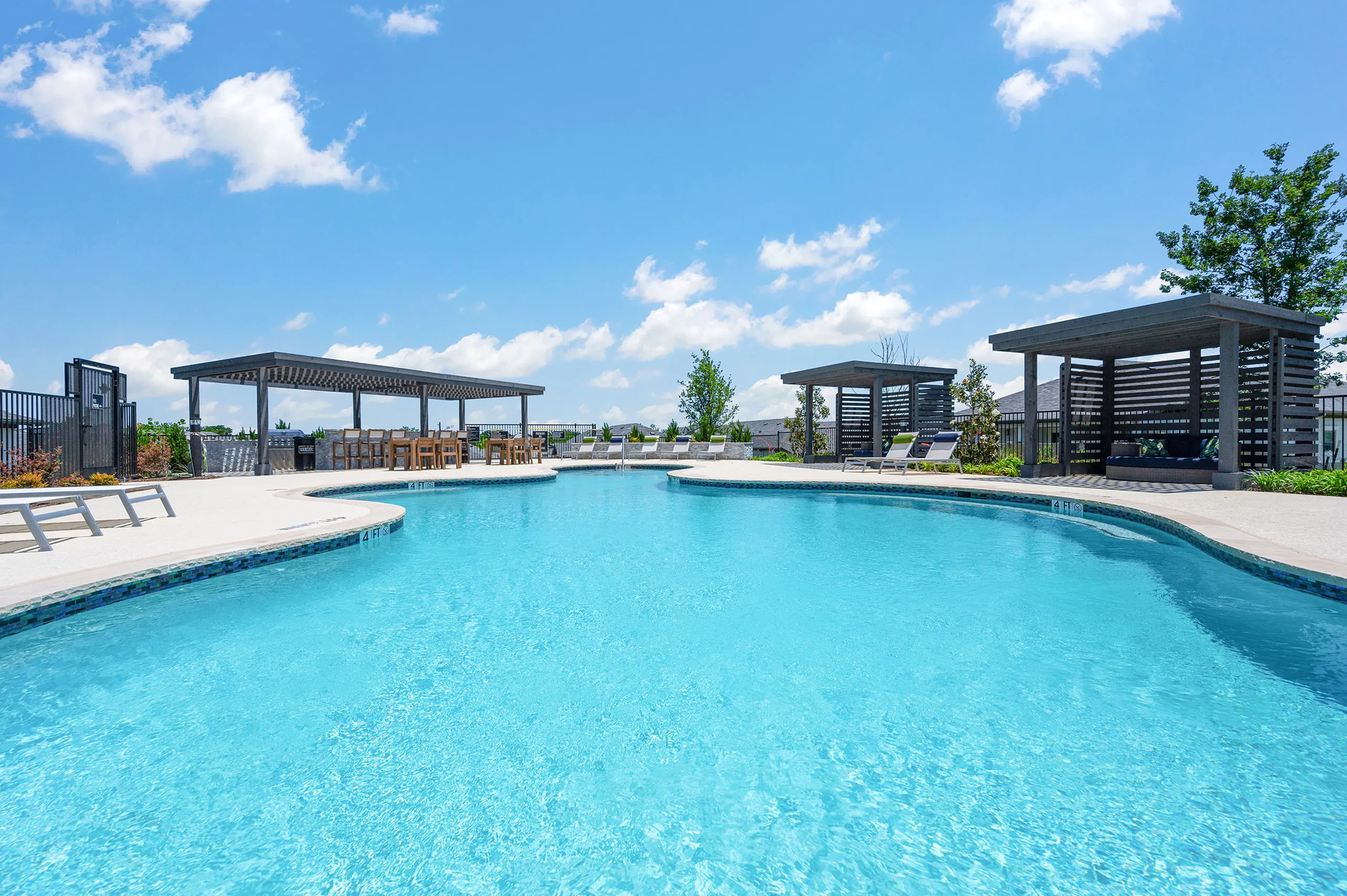 Luxurious outdoor swimming pool with stylish pergolas and sun loungers, set against a vibrant blue sky.