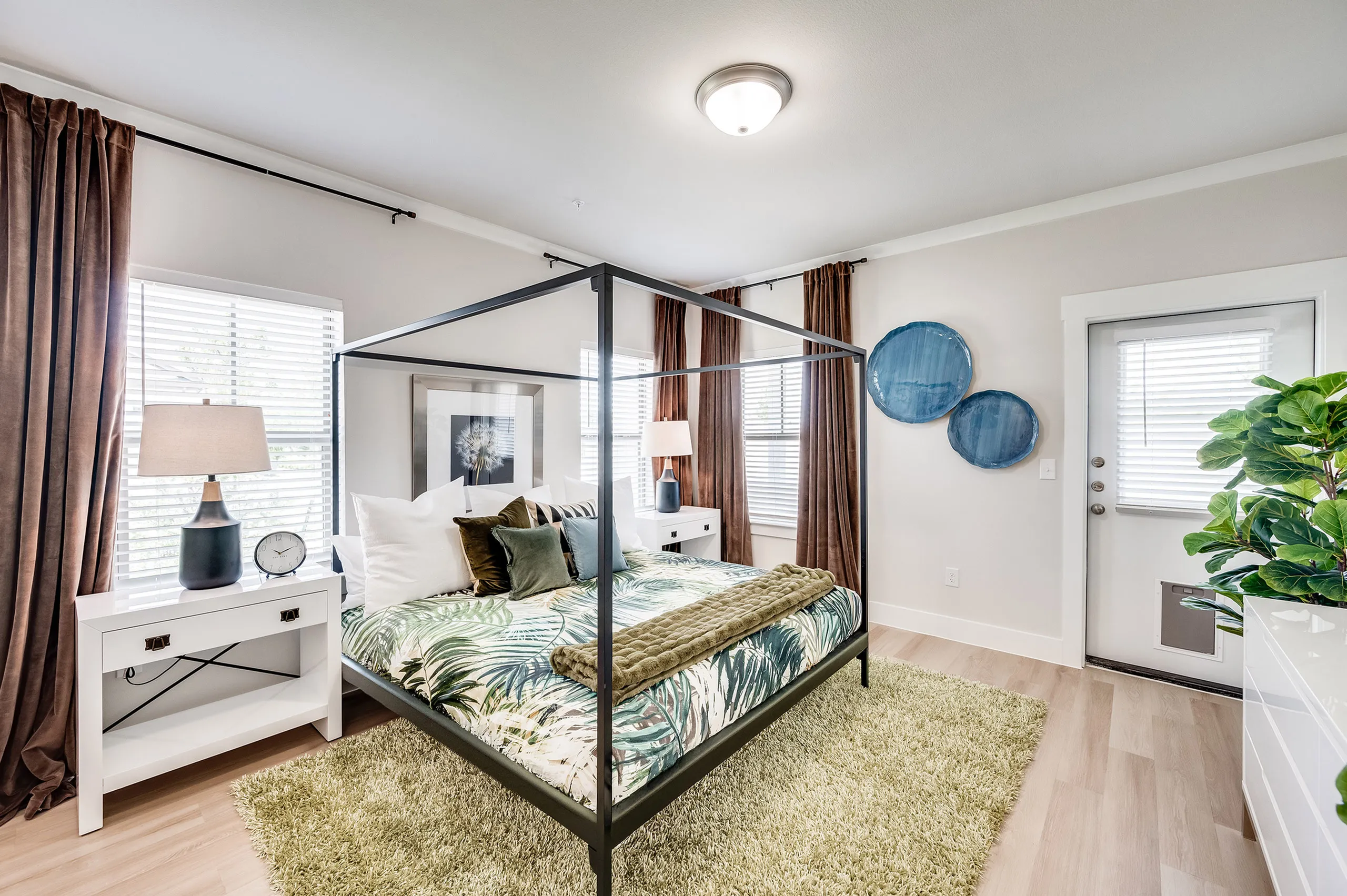 Chic bedroom with a stylish canopy bed, tropical-themed bedding, and abundant natural light, offering a serene retreat.