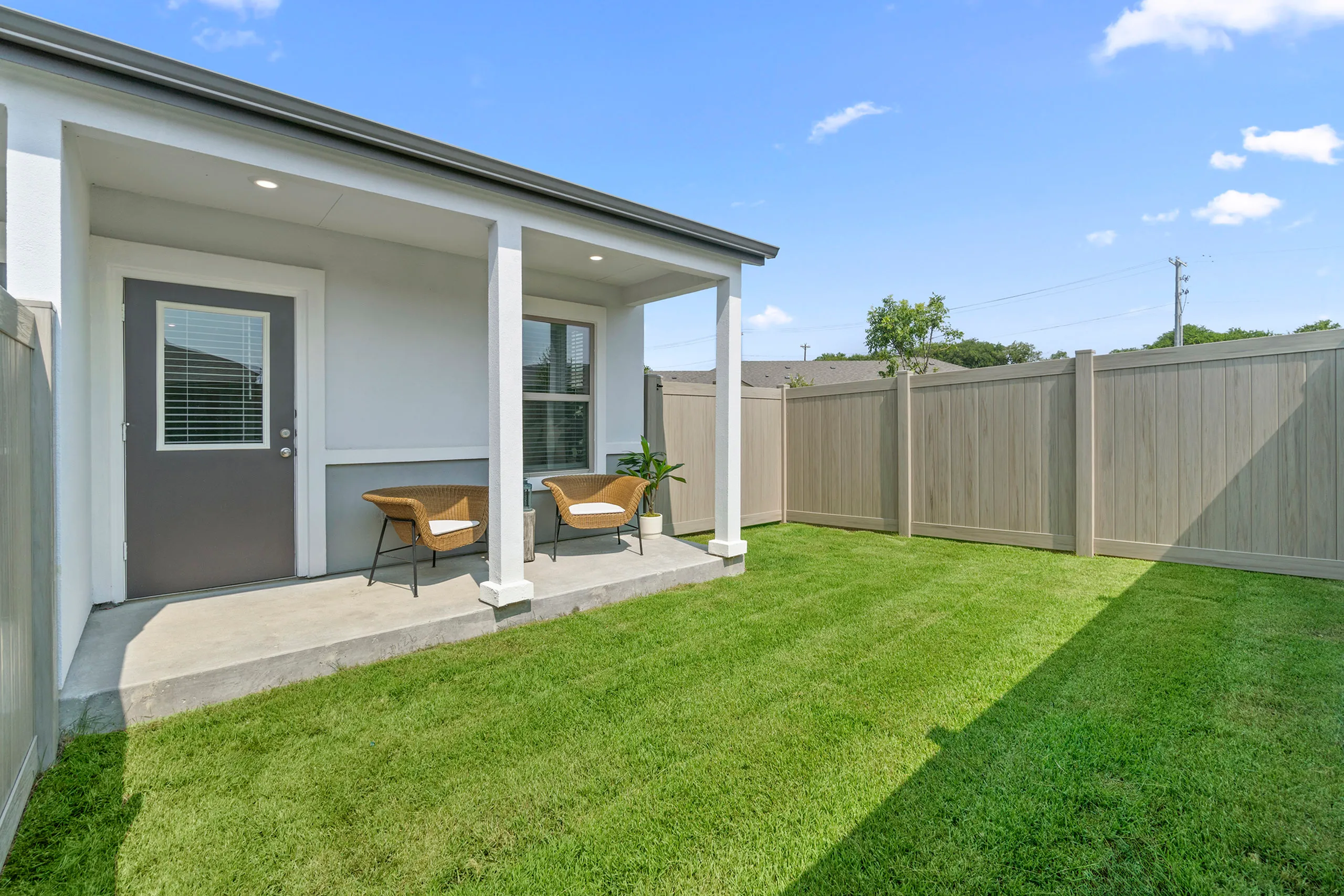 Charming backyard with lush green lawn and cozy patio chairs, perfect for relaxation and outdoor enjoyment.
