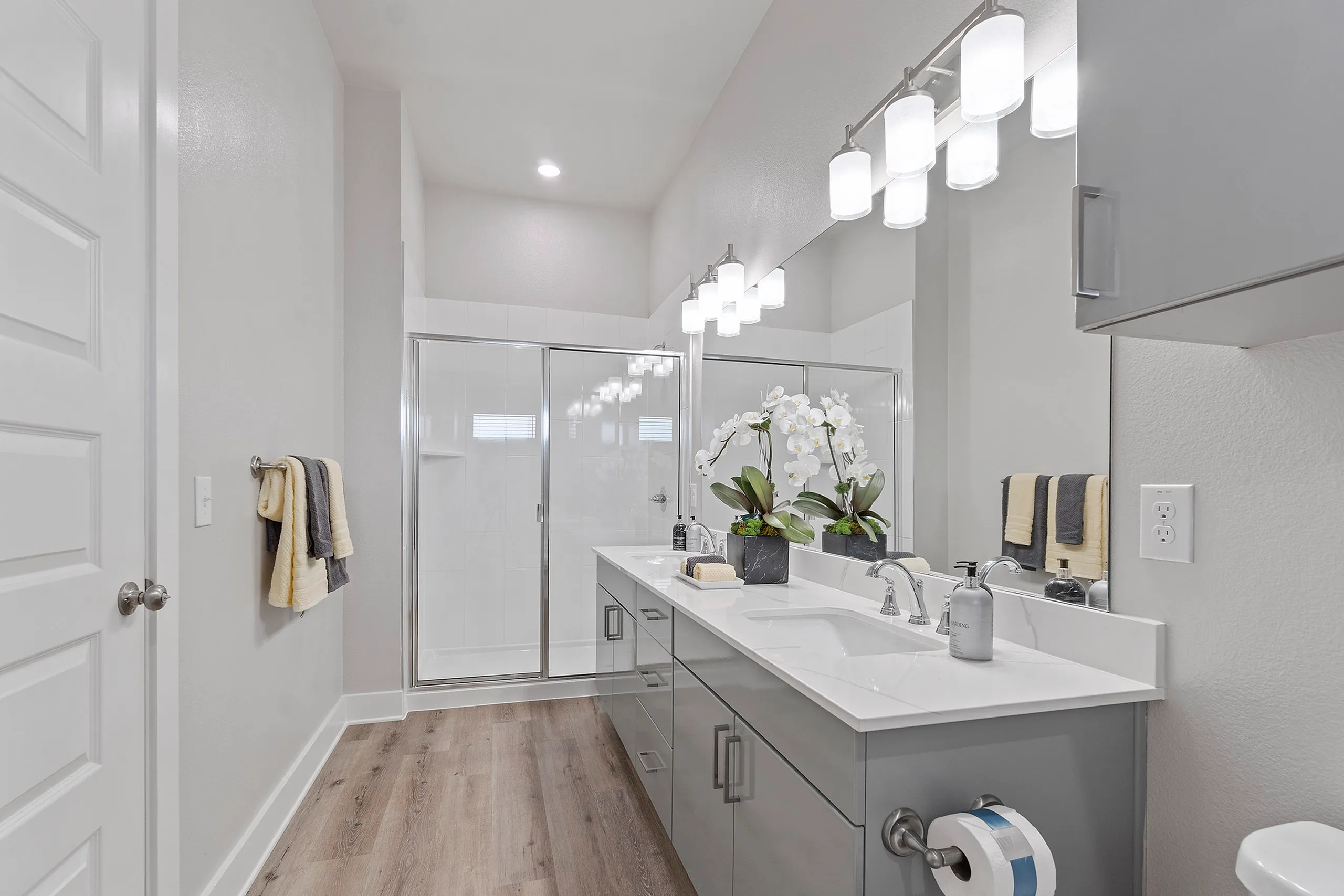 Elegant bathroom with dual sinks, modern fixtures, and chic glass shower in a bright and spacious design.