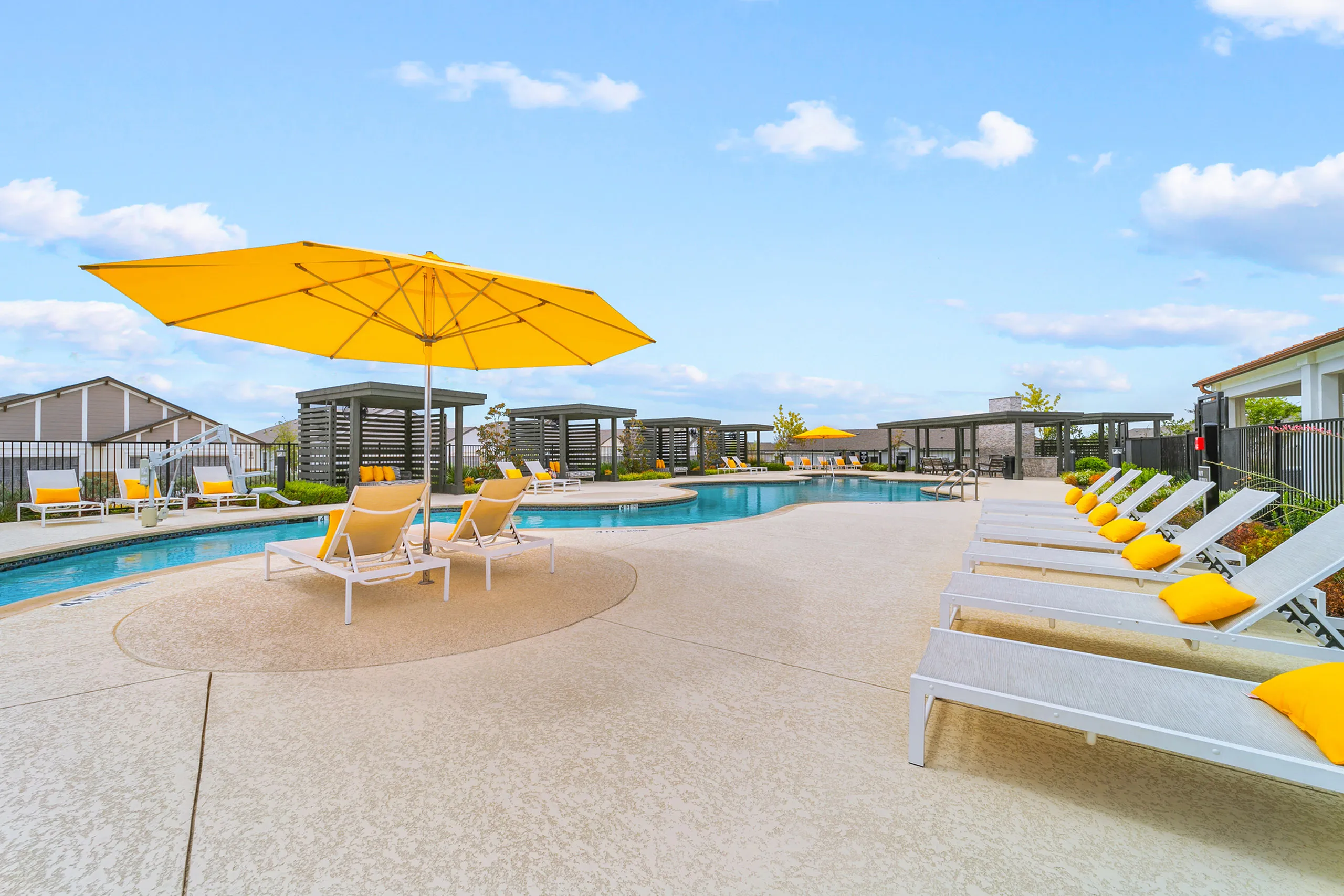 Inviting pool area with vibrant yellow umbrellas, modern lounge chairs, and serene blue skies offering a luxurious retreat vibe.