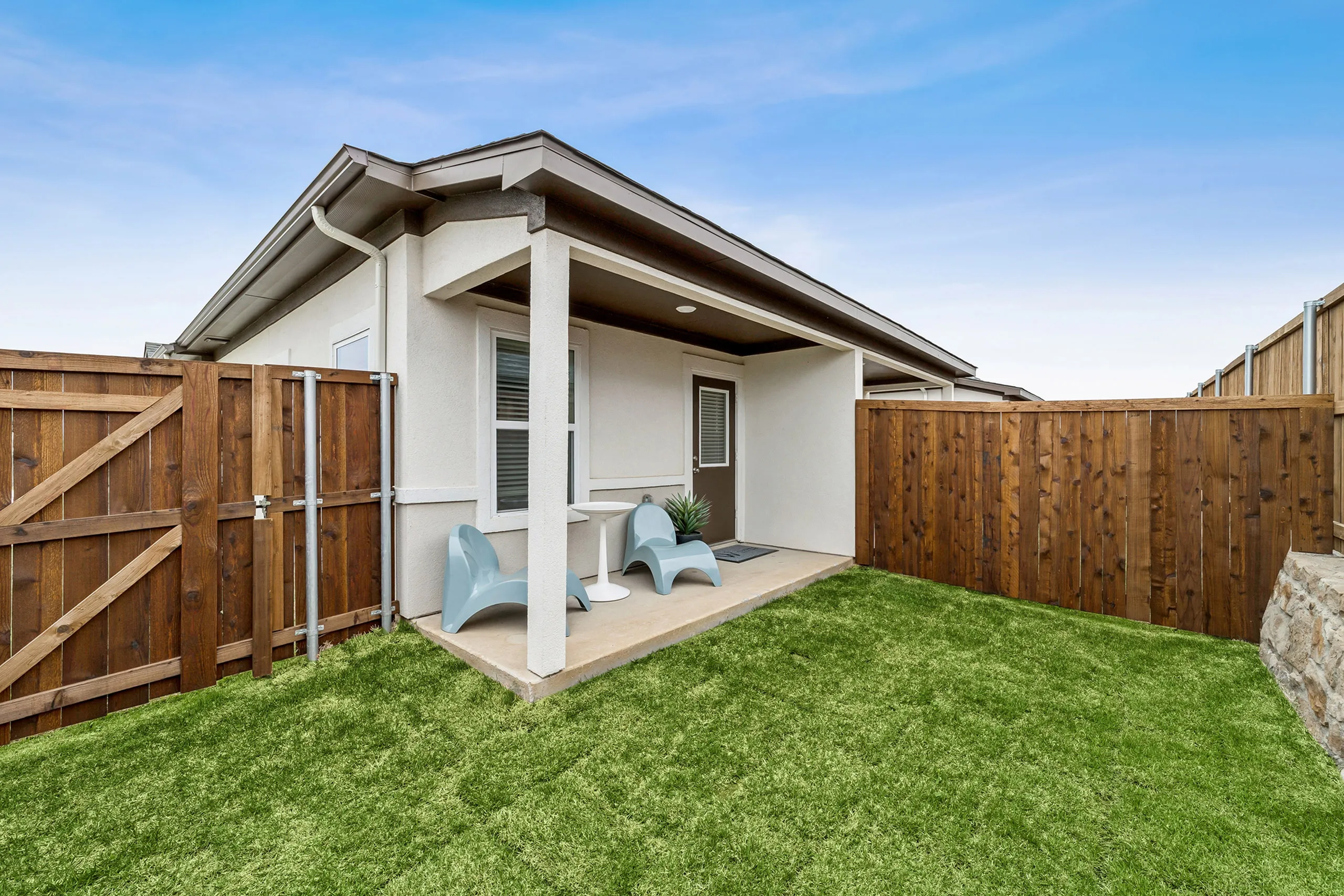 Charming outdoor patio with modern chairs and lush green lawn, perfect for relaxation and entertaining.