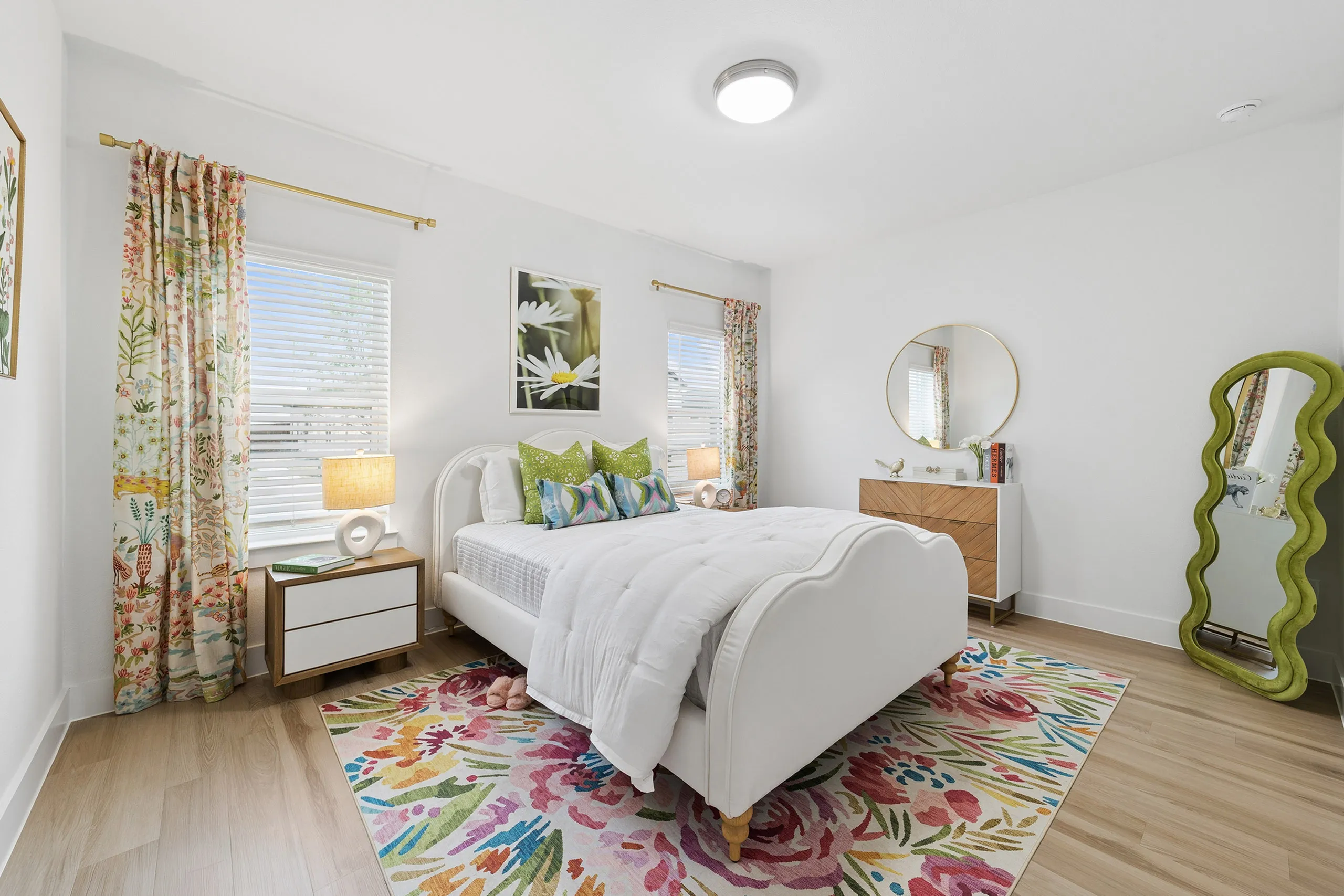 Beautifully decorated bedroom featuring a vibrant floral rug, elegant white bed, and stylish wall art, perfect for a cozy and inviting atmosphere.
