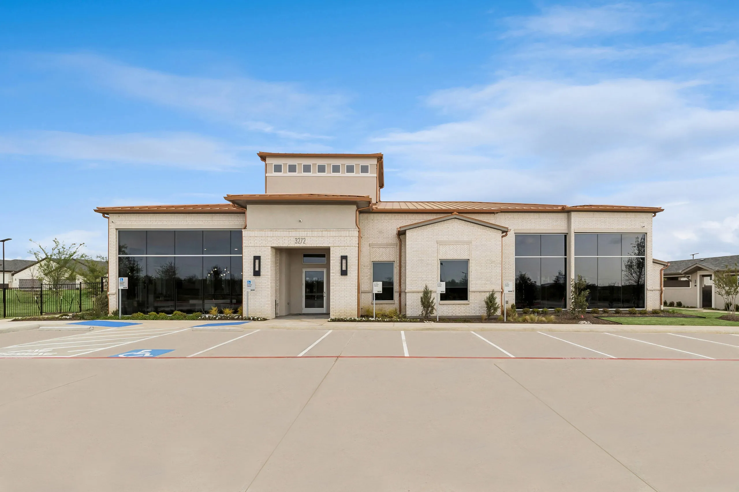 Elegant and modern residential building with large windows and a welcoming entrance, set against a clear blue sky.