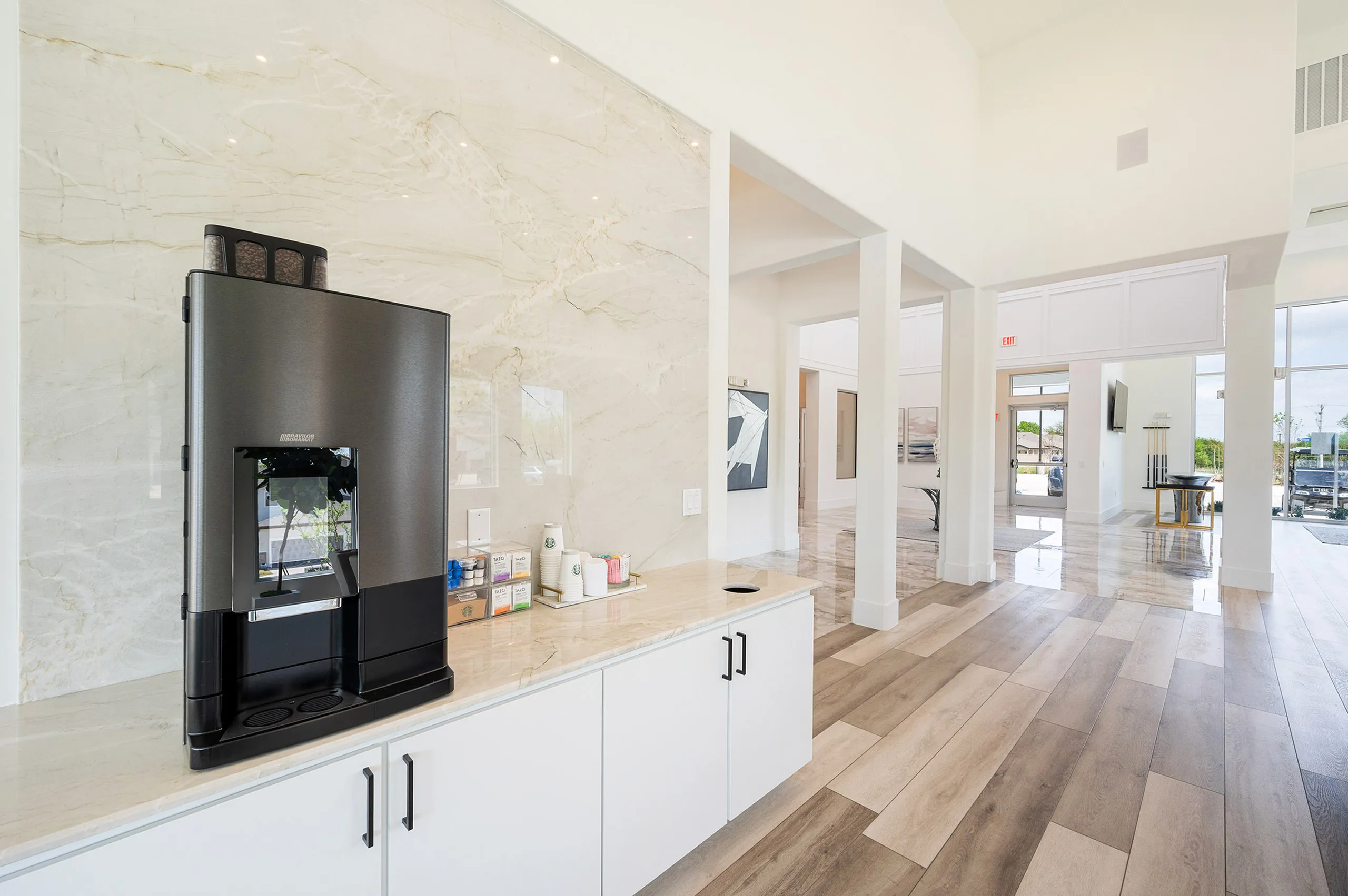 Bright and inviting open-concept community space with sleek coffee station and elegant wood flooring.