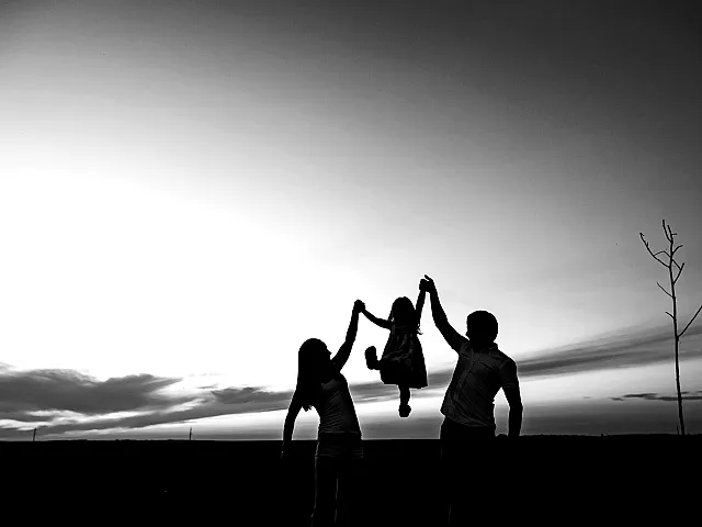 Heartwarming silhouette of a family enjoying a sunset, depicting joy and togetherness in a serene landscape.