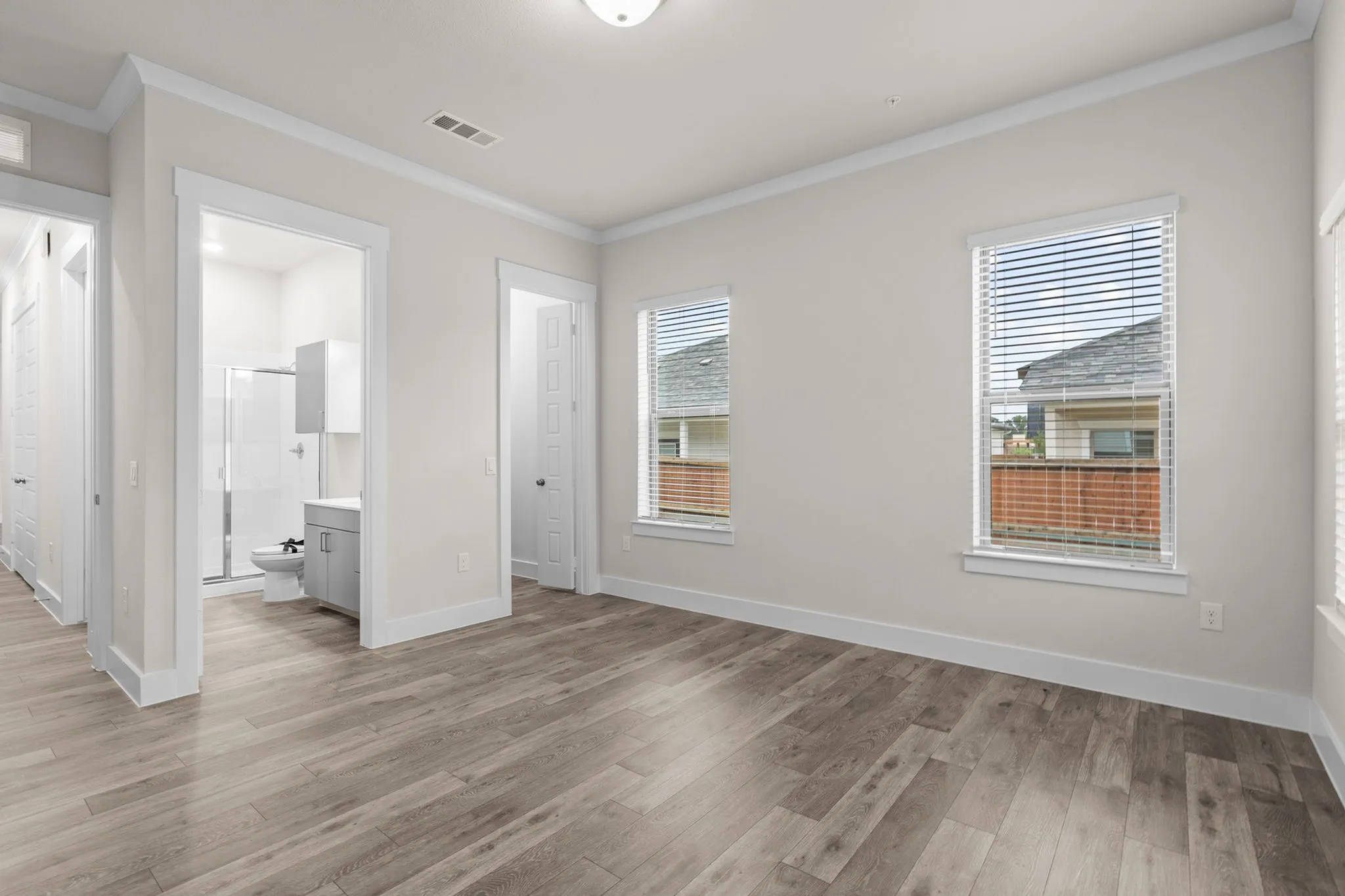 Bright, spacious bedroom with elegant hardwood floors, large windows, and sleek interior design, perfect for modern living | Apartments in Hutto, TX | Mansions Eight65