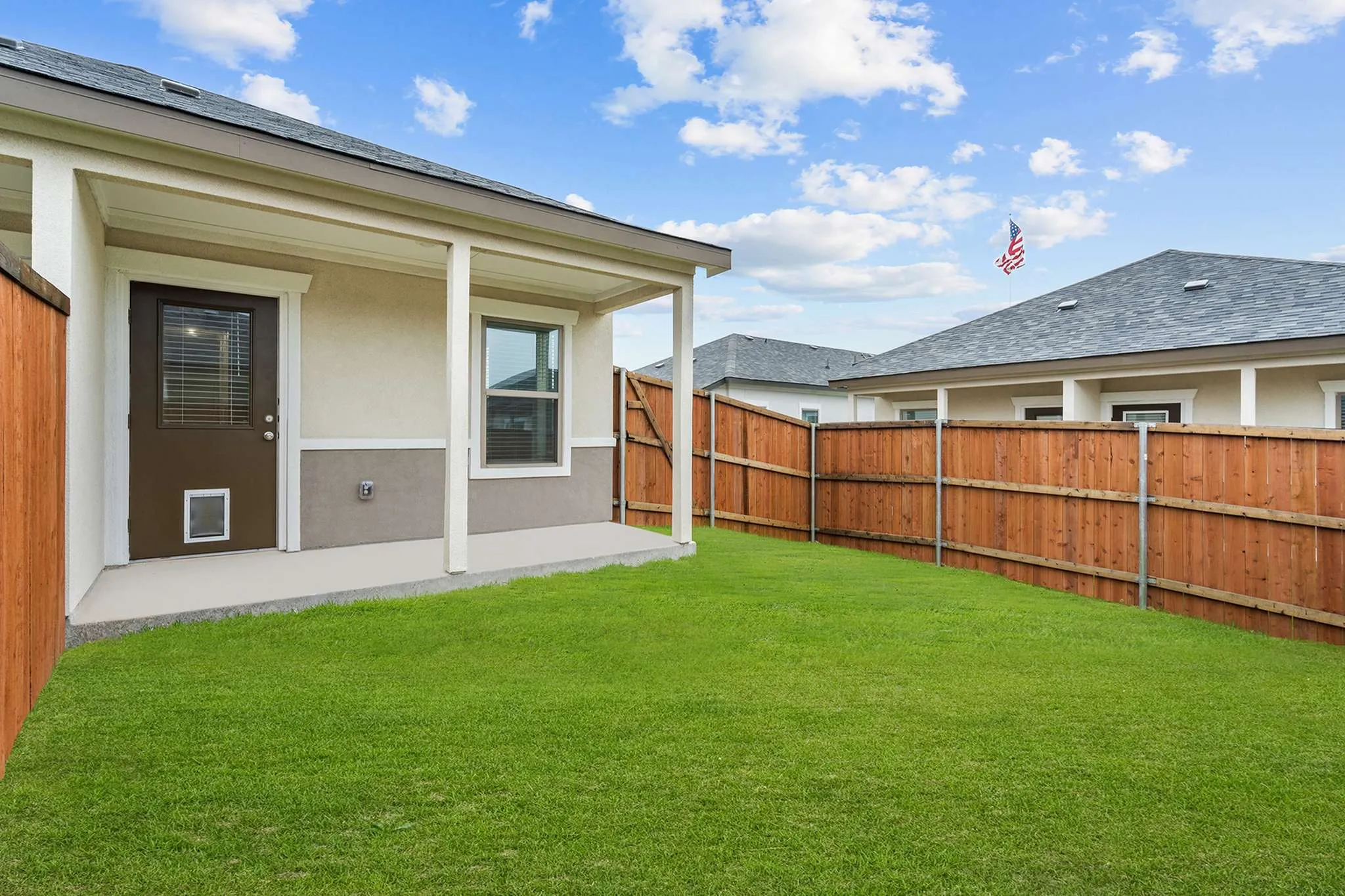 Charming backyard view with a lush green lawn, wooden fence, and a cozy porch, perfect for outdoor relaxation | Apartments in Hutto, TX | Mansions Eight65