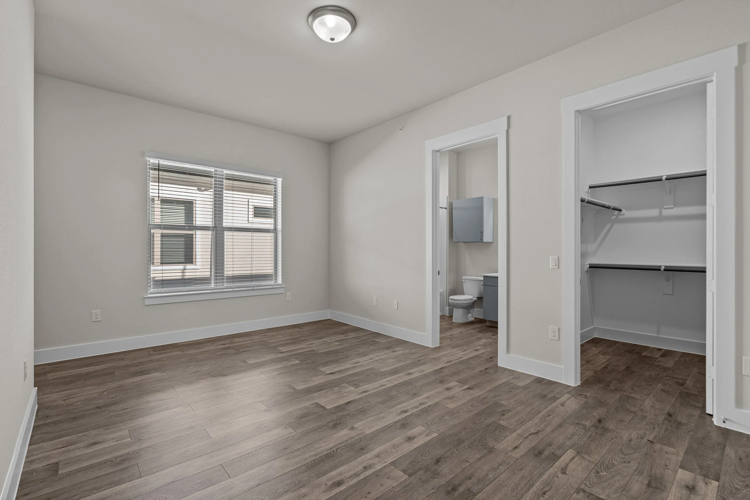 Bright and inviting bedroom with hardwood floors, featuring a spacious walk-in closet and private bathroom.