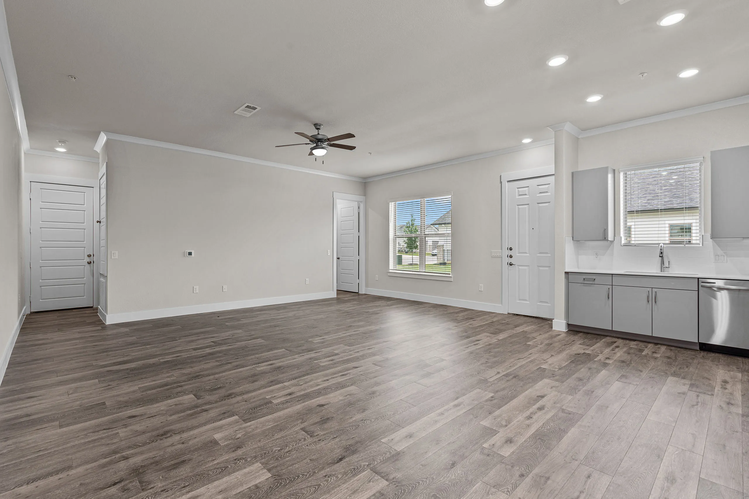 Modern open-concept living area with elegant hardwood floors, ceiling fan, and sleek kitchen cabinets.
