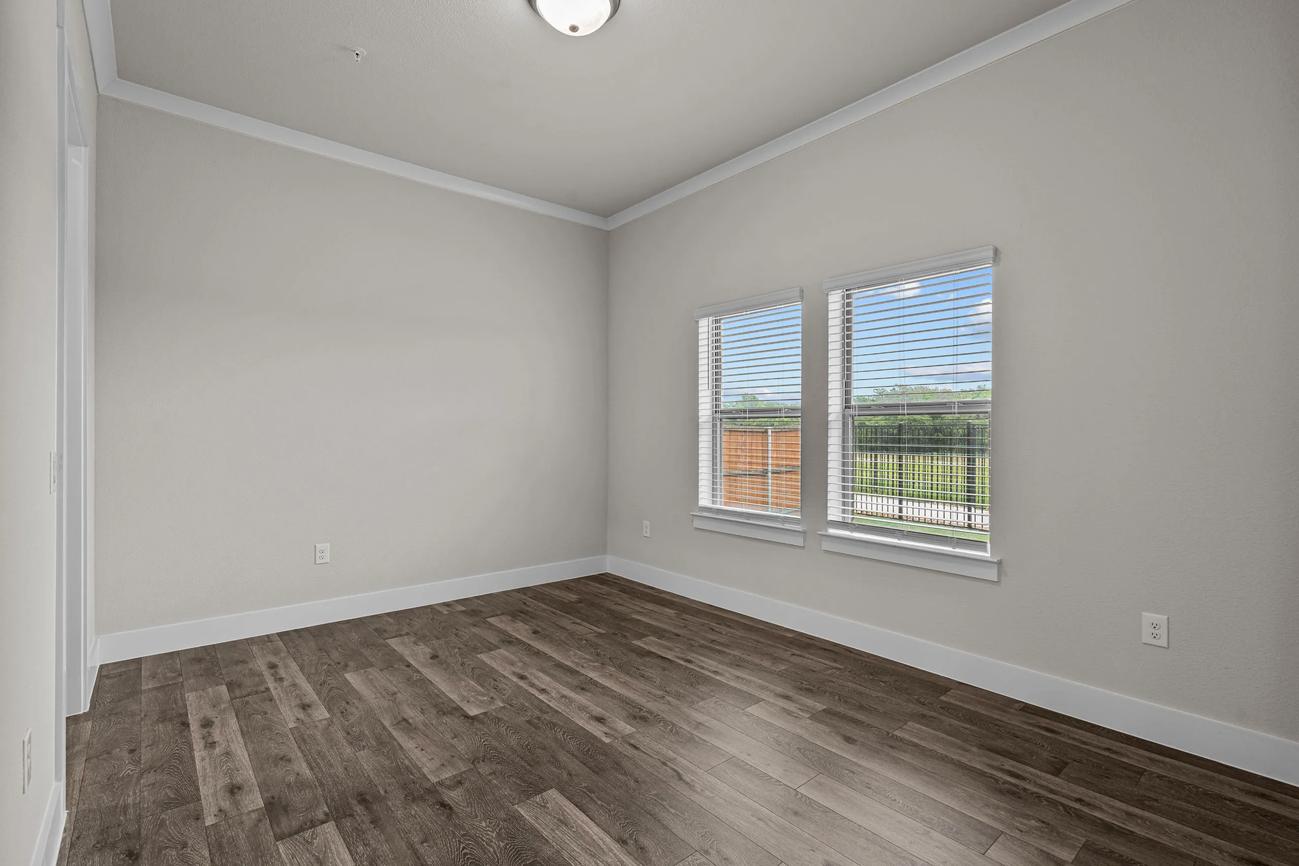 Bright and inviting Bedroom featuring sleek wood-like floors, large windows, and modern neutral walls.