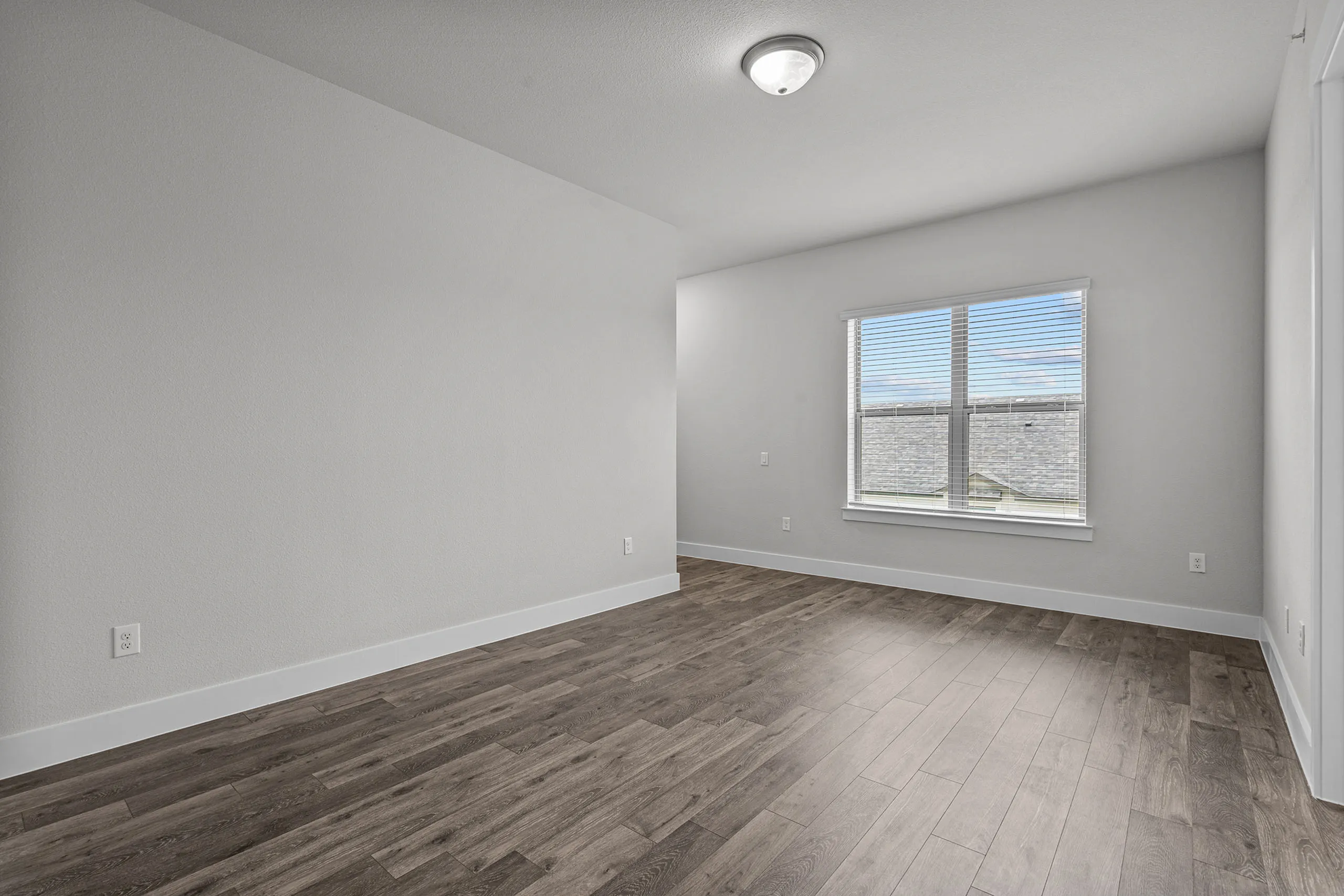 Bright and airy room with elegant wood flooring and a large window inviting natural light.