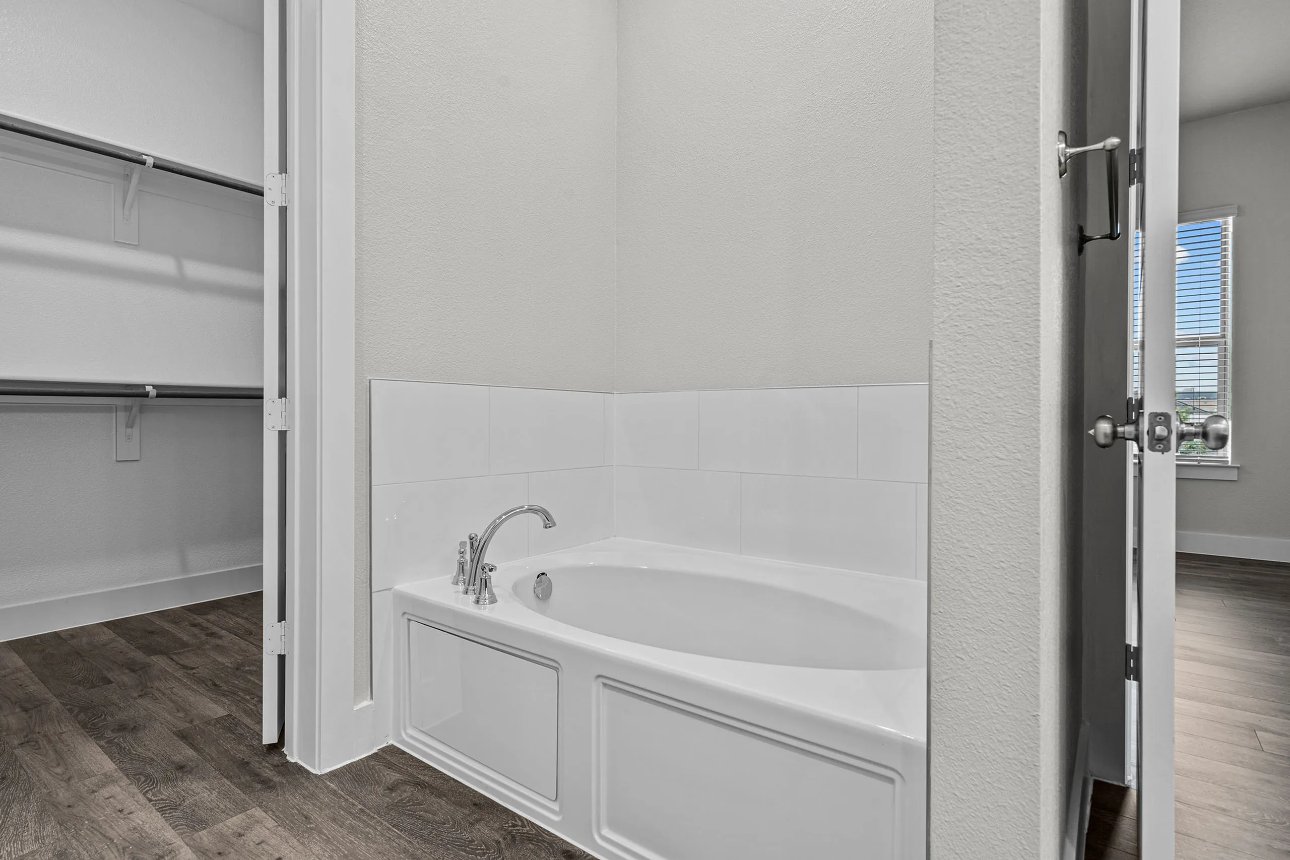 Sleek bathroom featuring a modern bathtub and adjacent walk-in closet in a bright, airy apartment setting.