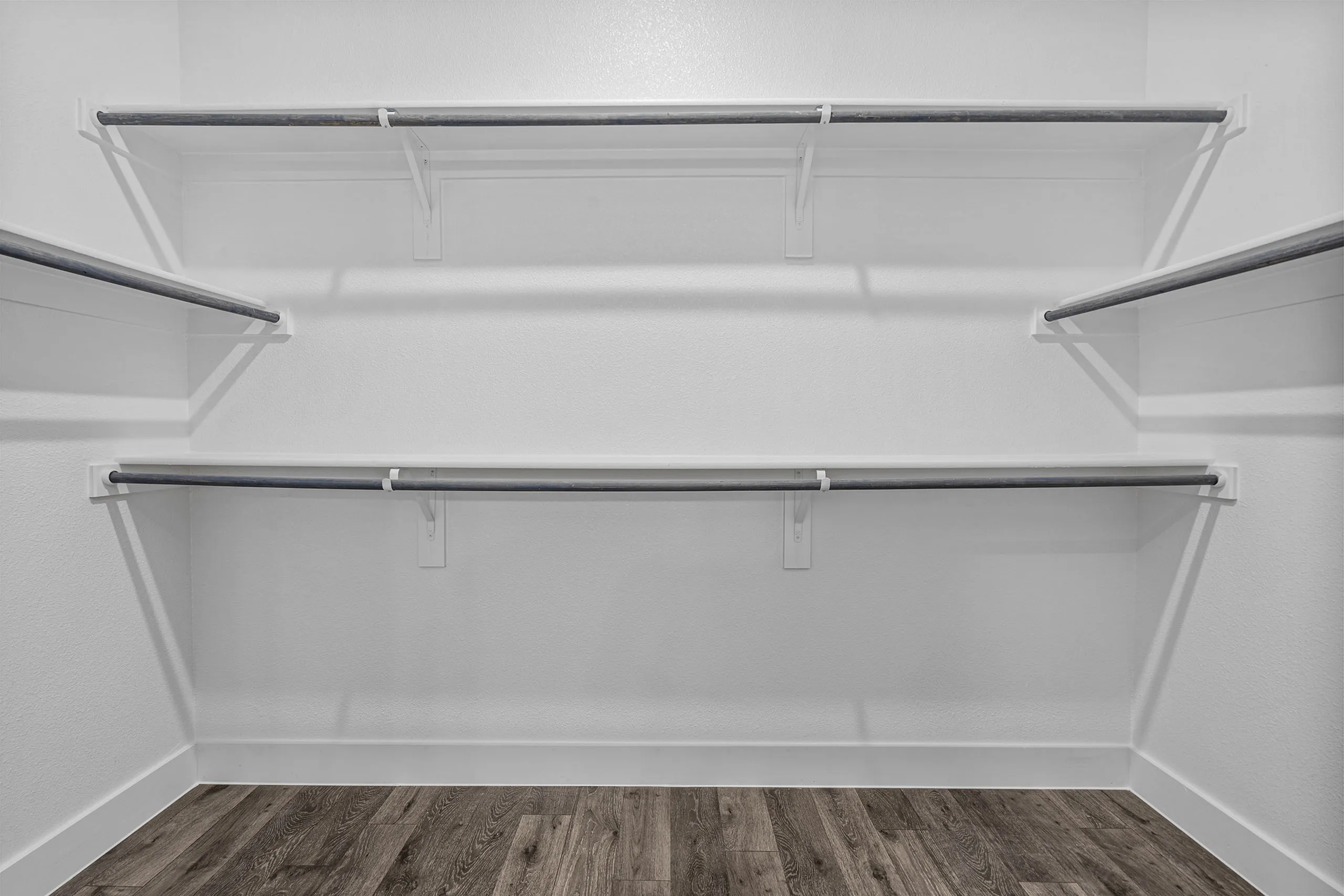 Spacious walk-in closet with multiple shelves and wooden flooring, perfect for organizing and maximizing storage in your home.