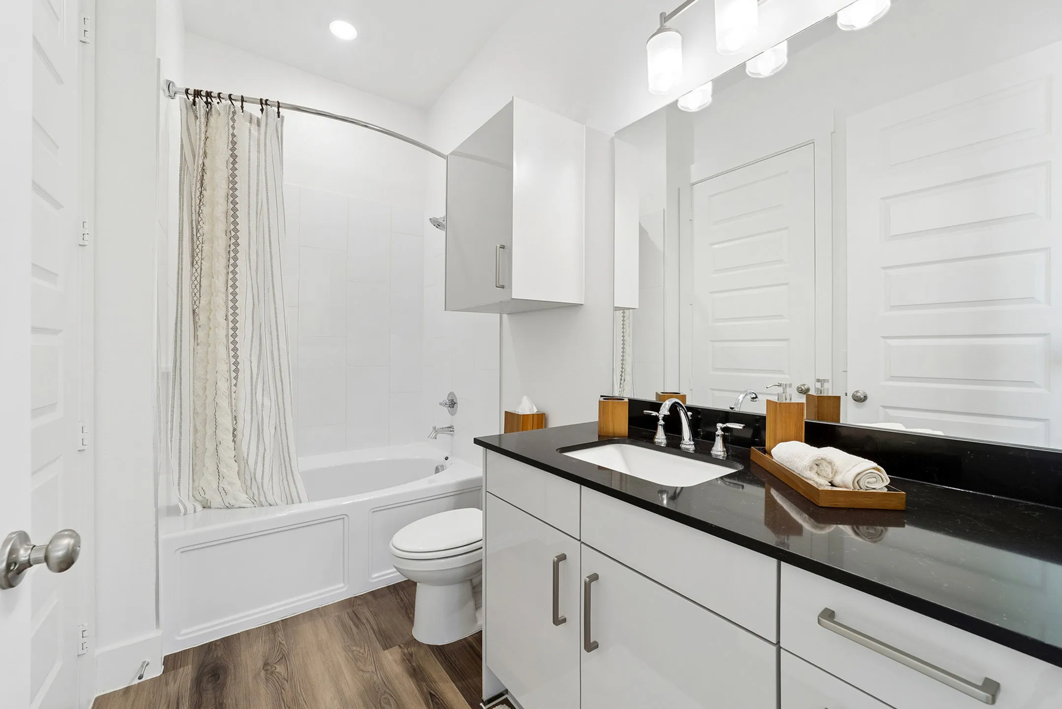 Elegant bathroom featuring sleek black countertop, modern fixtures, and a cozy bathtub with a stylish curtain.