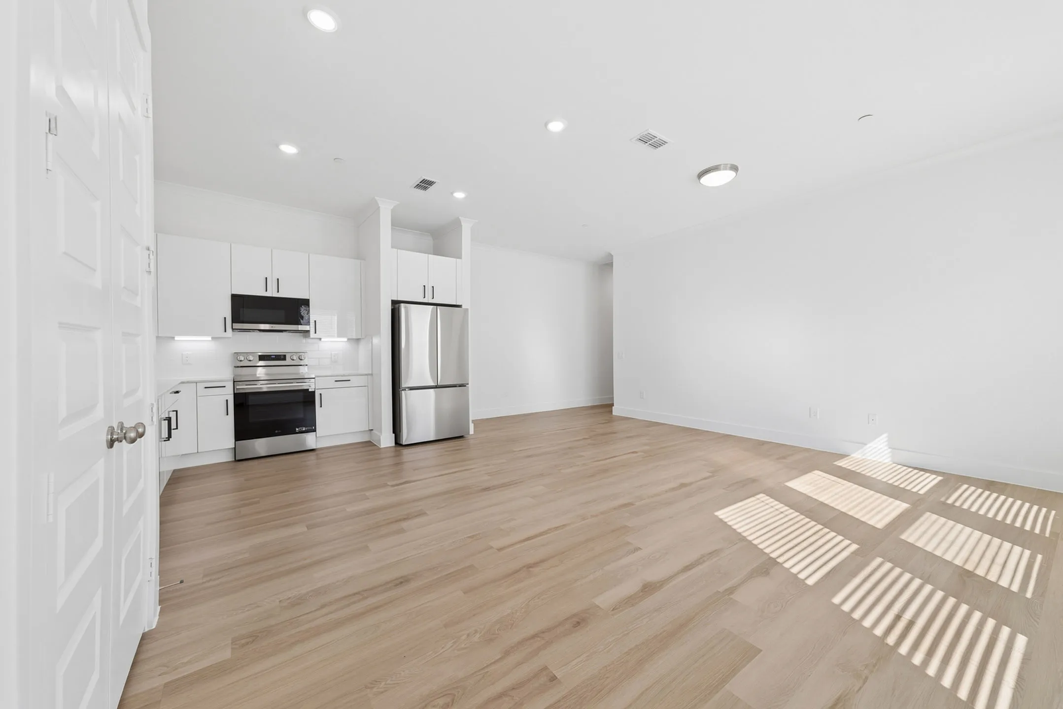 Sleek modern kitchen with stainless steel appliances and open layout complemented by elegant wood flooring.