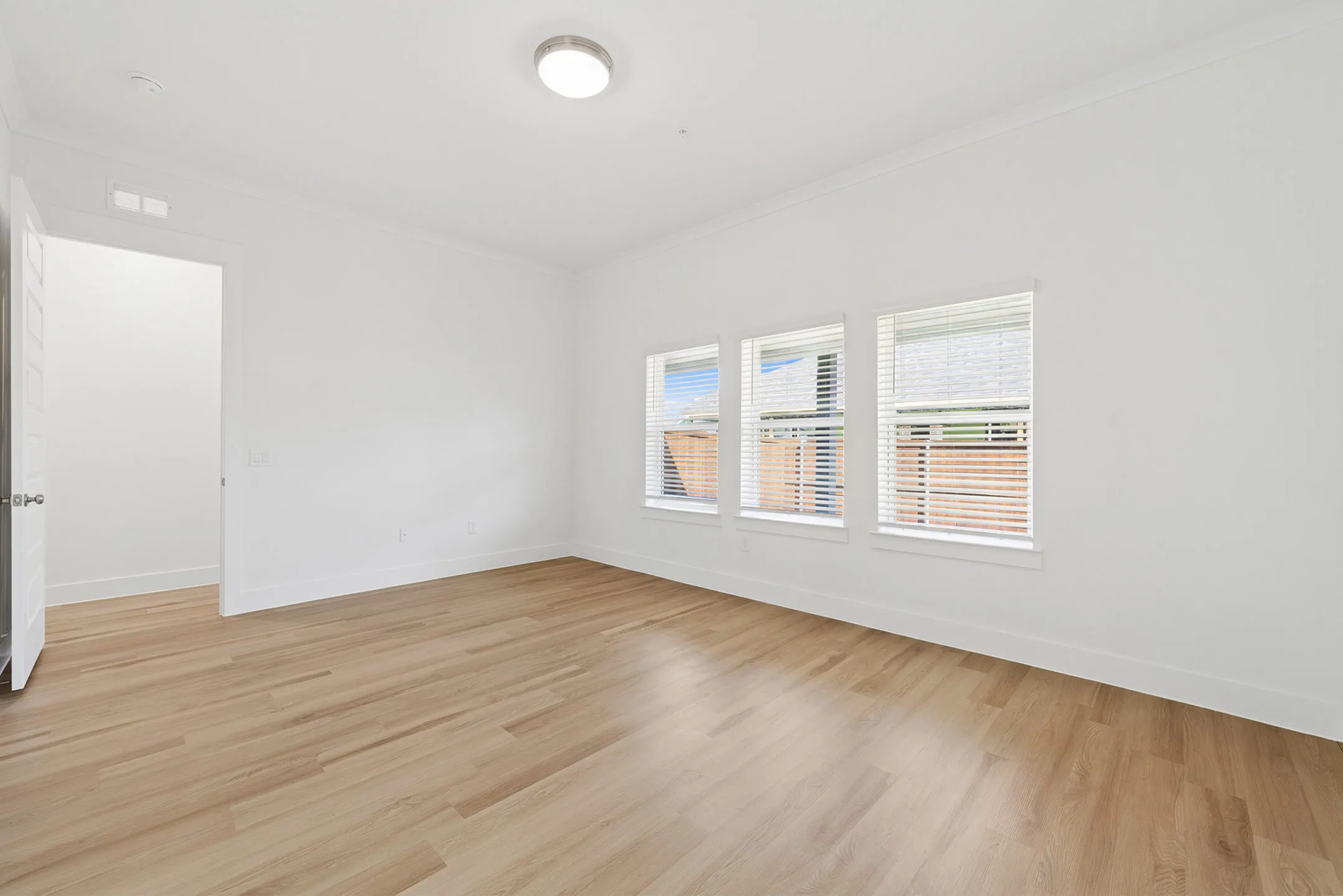 Bright and spacious empty room with large windows and elegant hardwood floors.