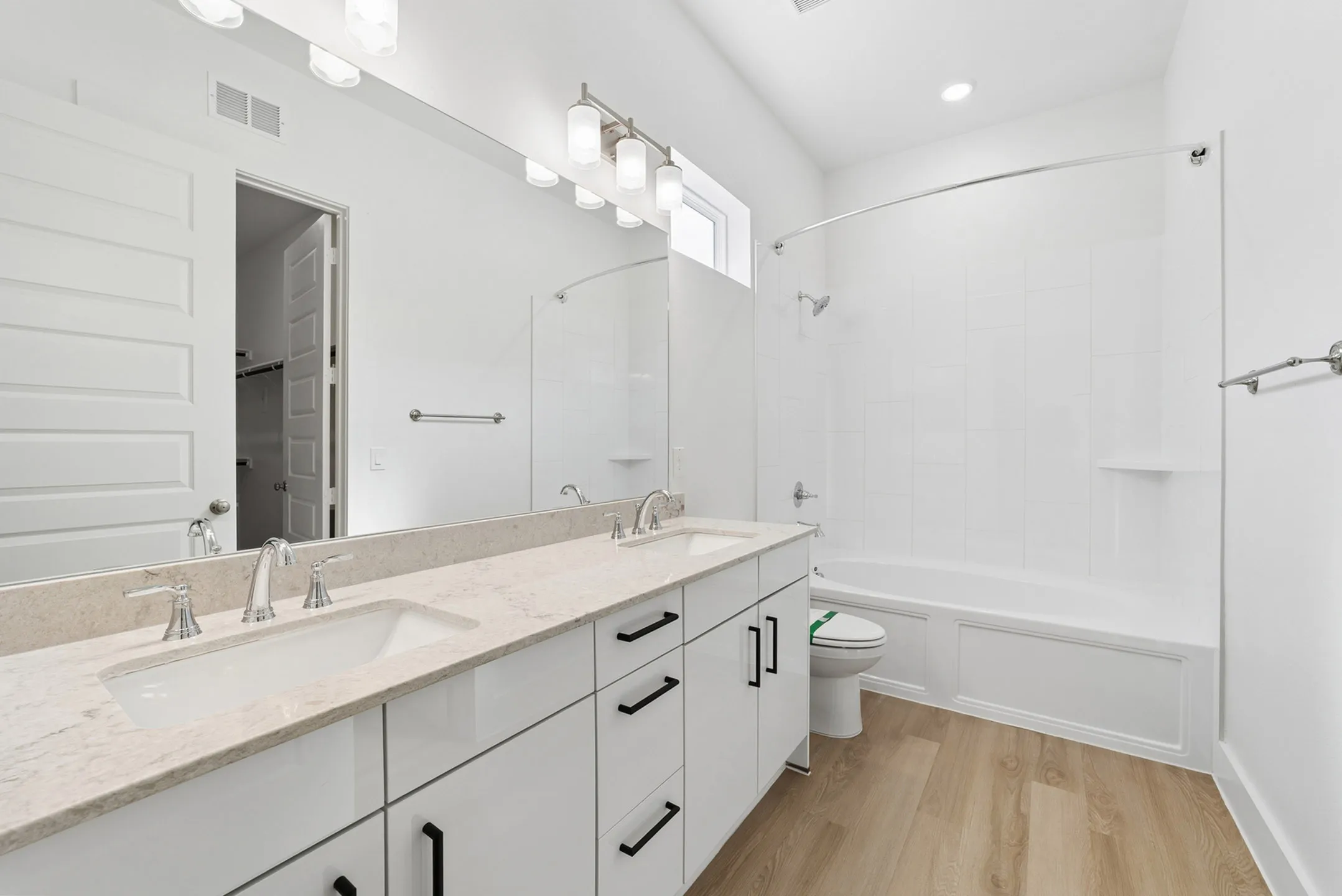 Elegant contemporary bathroom with dual sinks, stylish vanity, and bright lighting enhancing the sleek design.