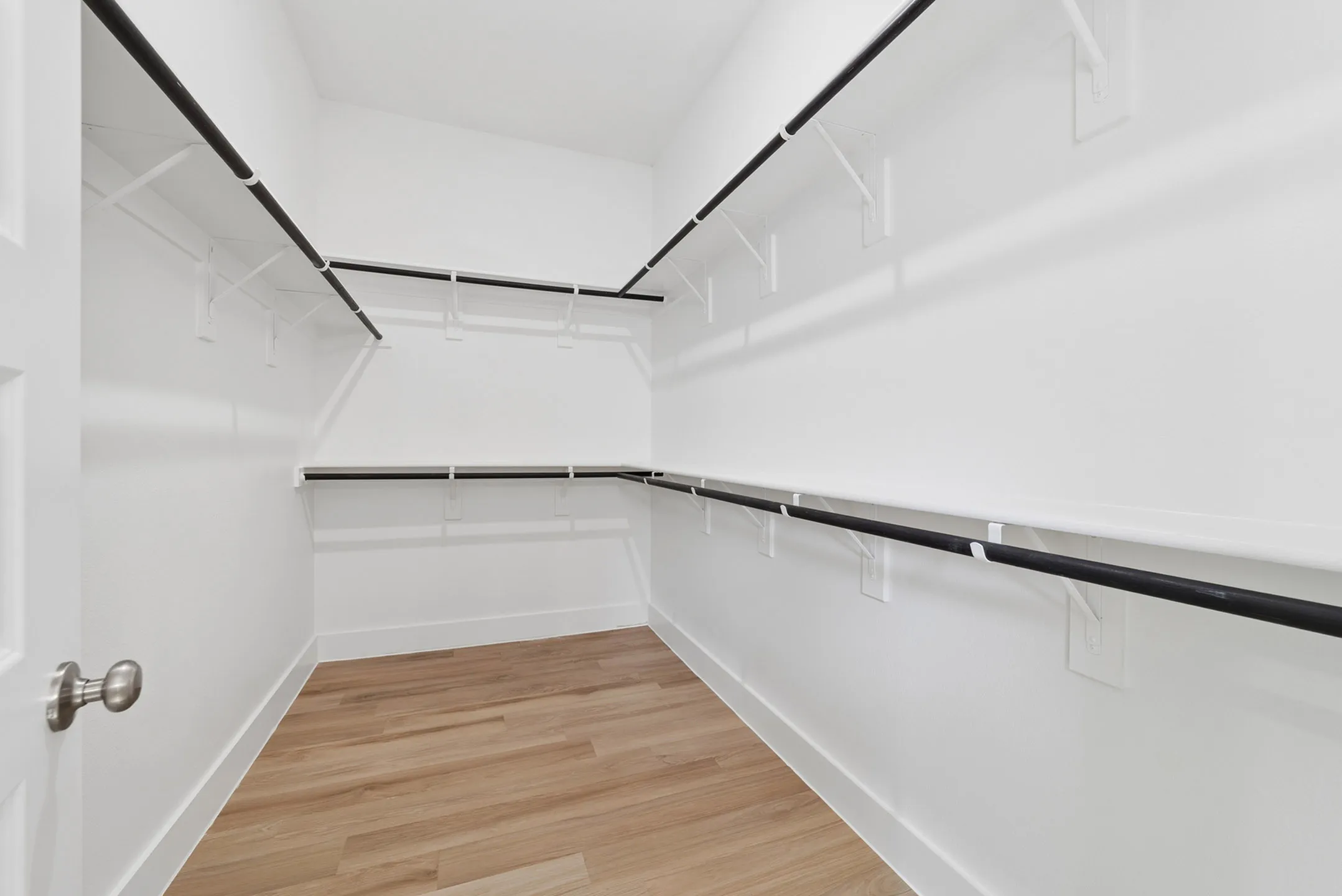 Spacious walk-in closet with elegant wooden flooring and ample shelving for versatile storage solutions.