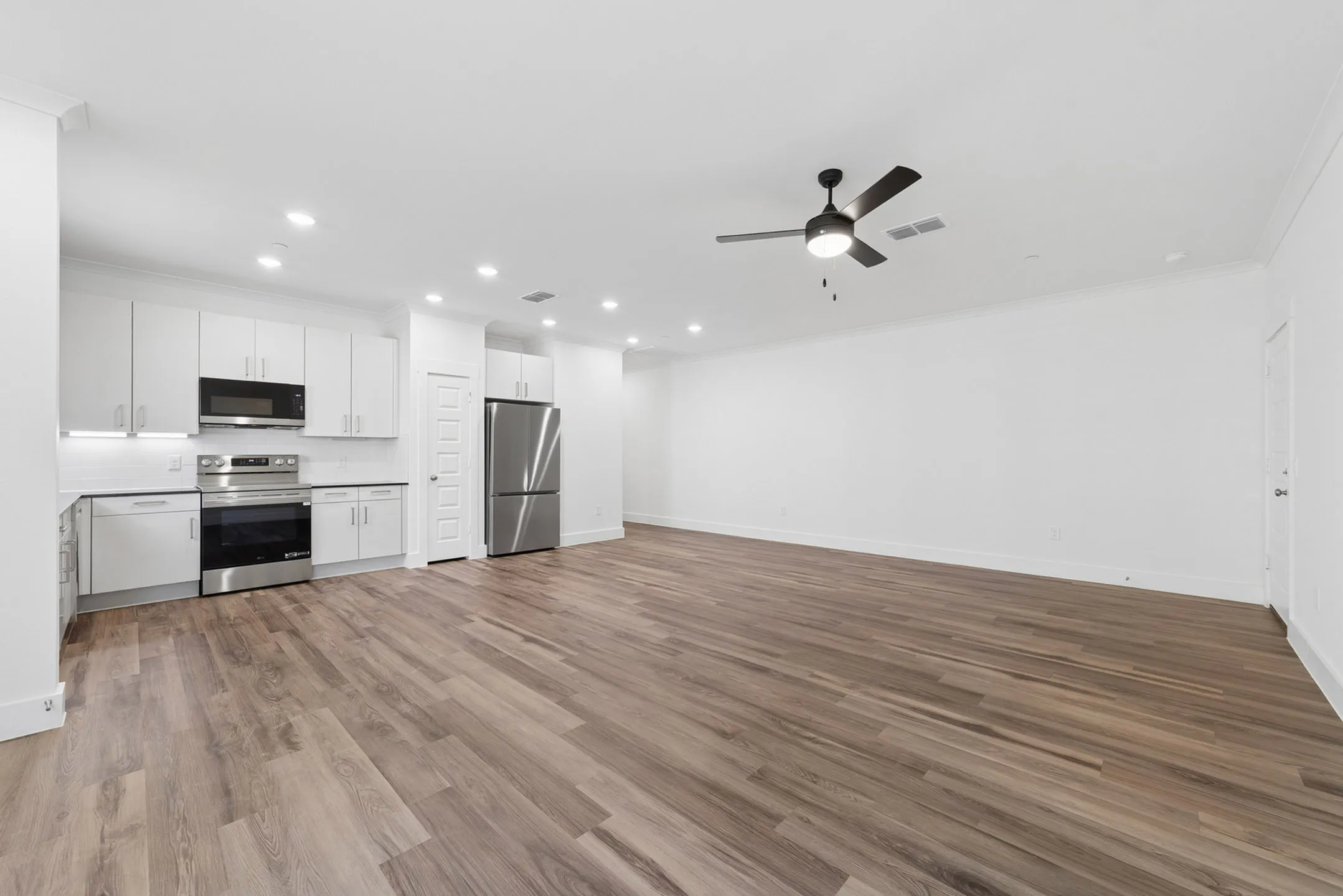Modern open-concept living area featuring sleek kitchen with stainless steel appliances and elegant wood flooring.
