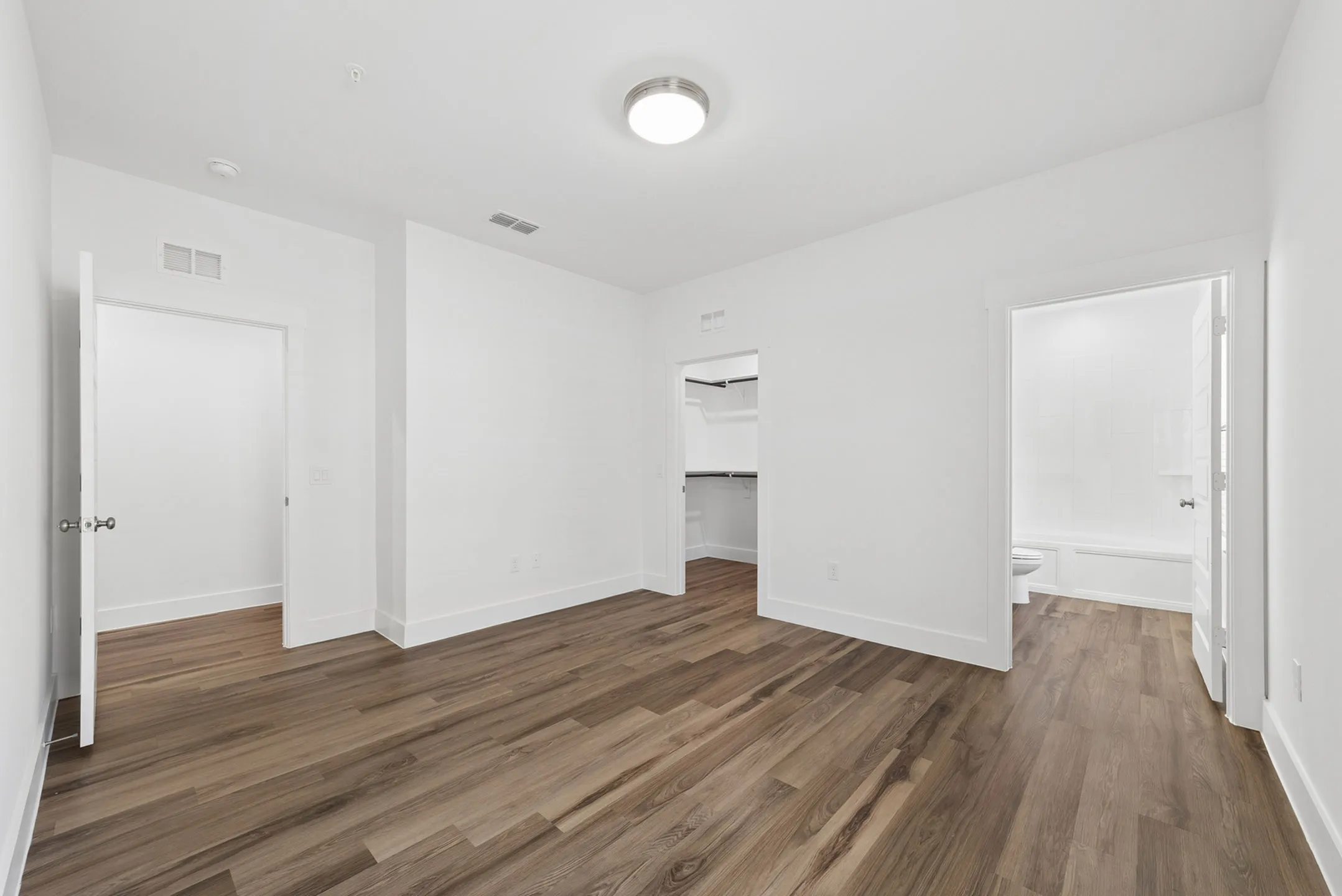 Bright and spacious bedroom with elegant wood flooring, walk-in closet, and ensuite bathroom.