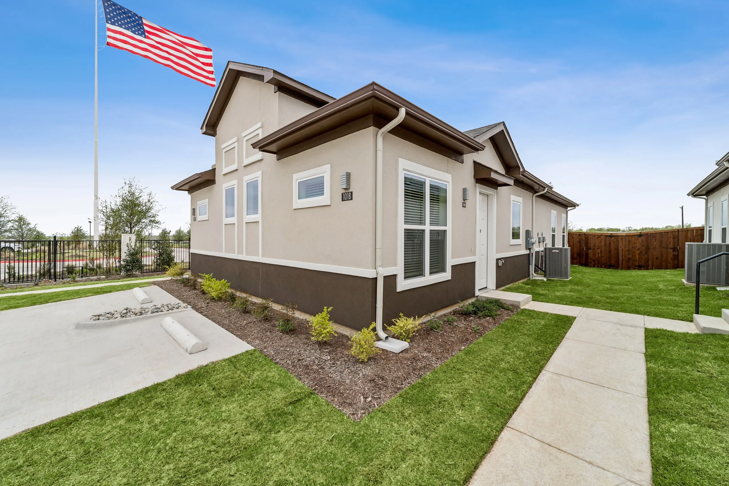 Charming single-story house with manicured lawn and vibrant surroundings, showcasing a welcoming front path and modern architectural design.