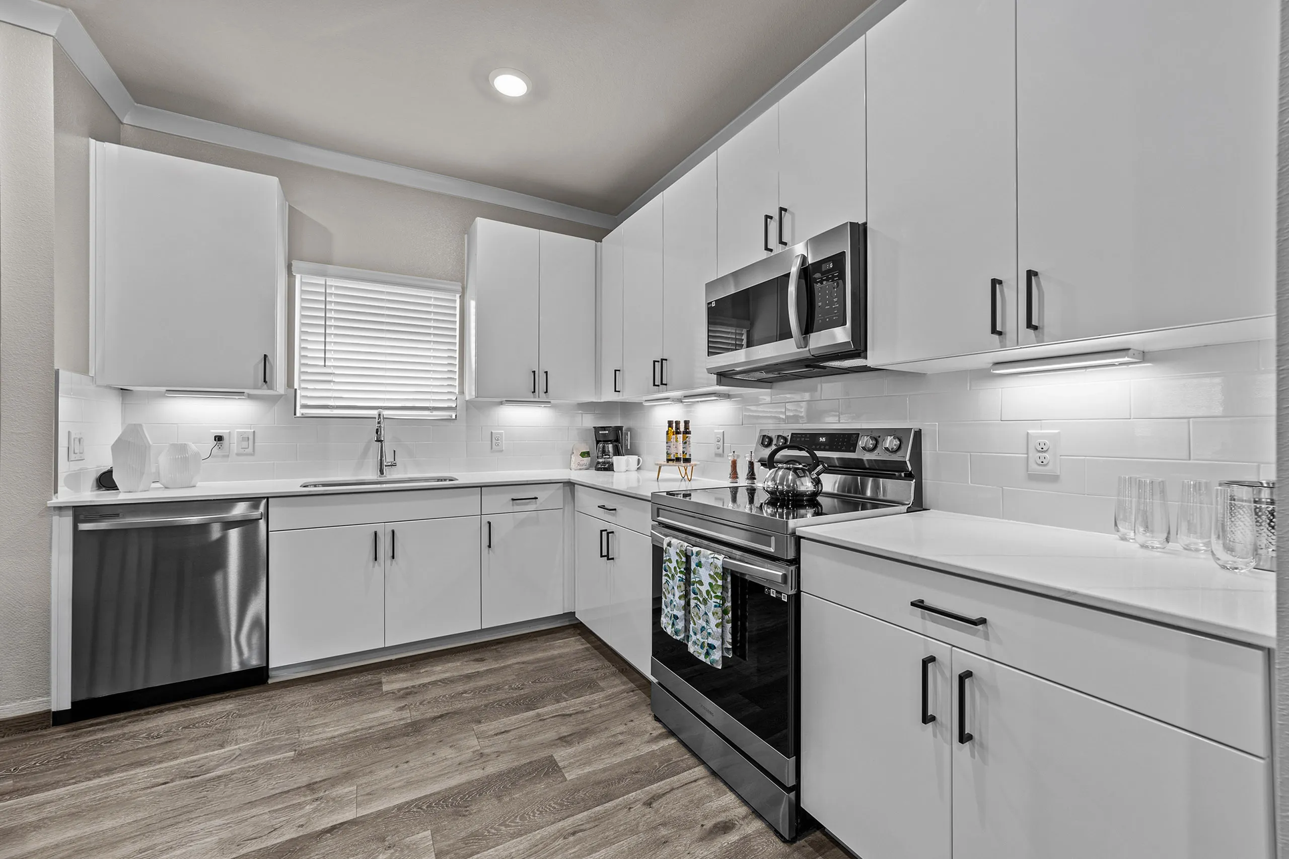 Sleek modern kitchen with white cabinetry, stainless steel appliances, and elegant wood flooring.