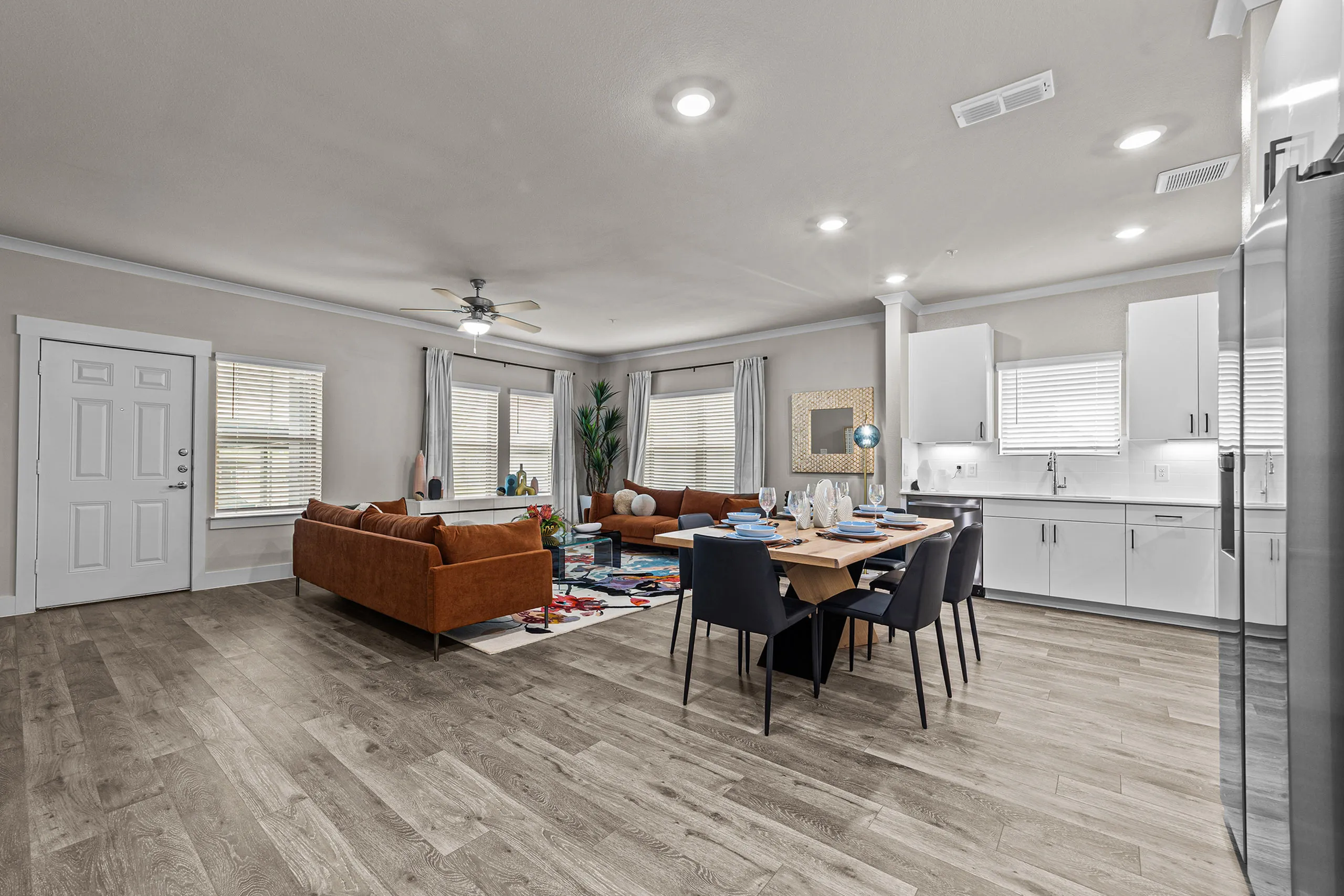 Elegant open-concept living area with modern kitchen, stylish dining space, and cozy seating, featuring warm wood flooring and neutral decor.