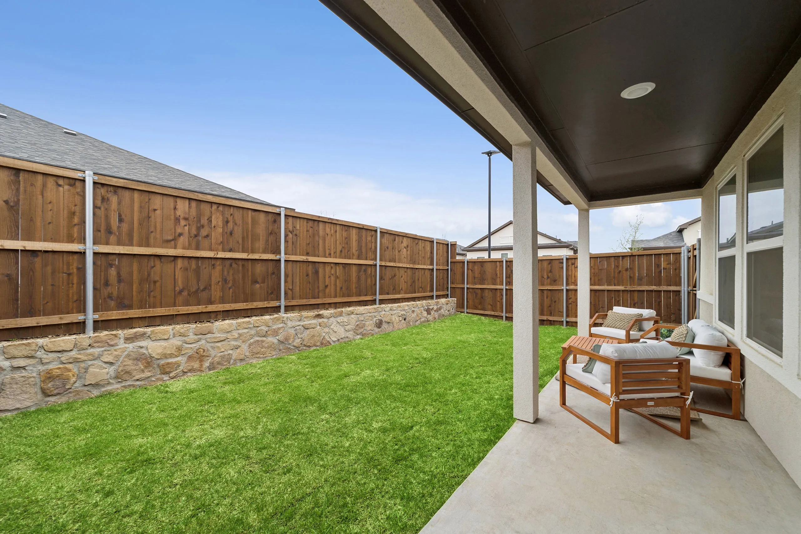 Inviting backyard patio with cozy seating, lush green lawn, and stylish wooden fencing for privacy.