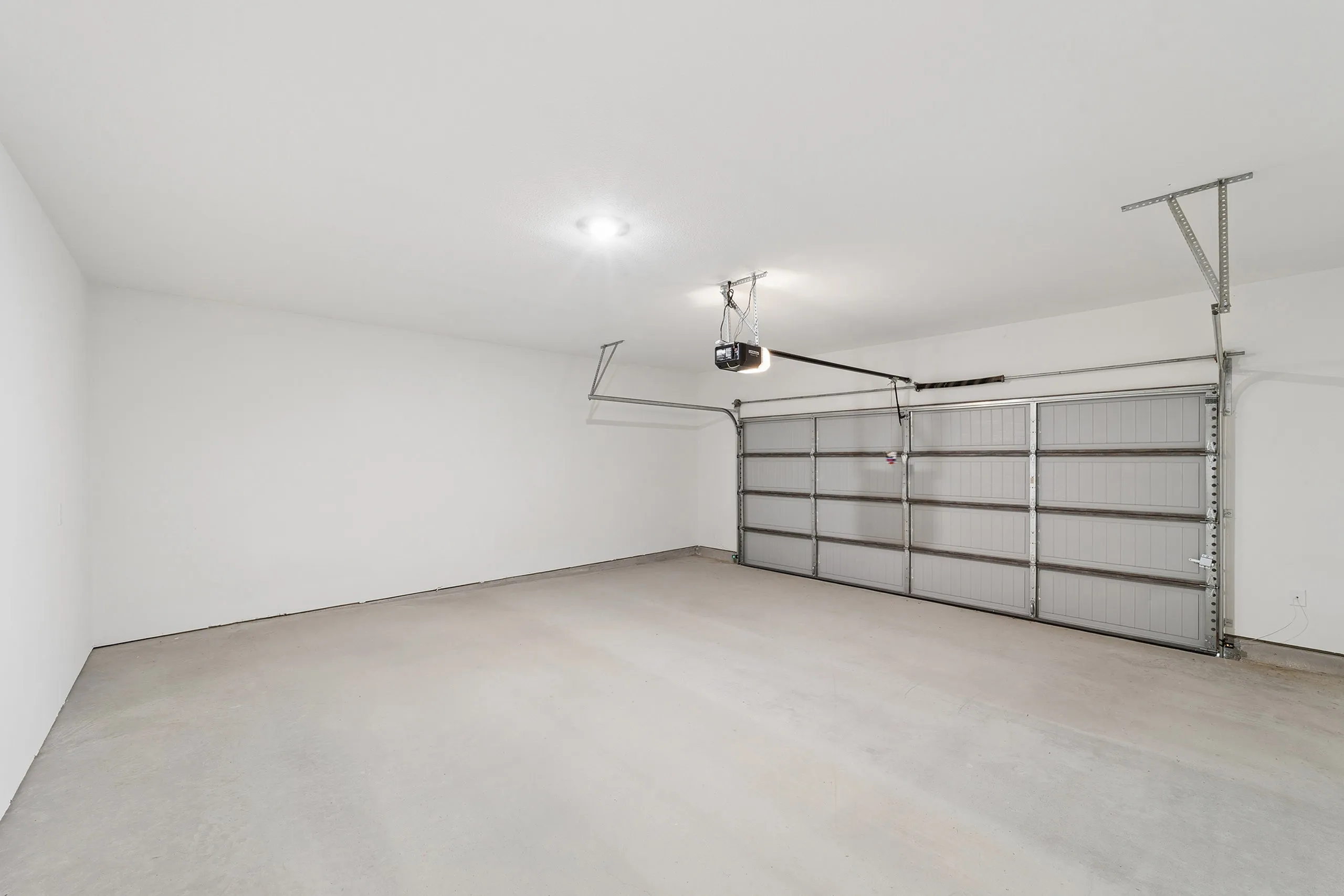 Spacious modern garage with clean concrete flooring and a double-door entrance. Ample room for vehicles and storage in a contemporary layout.