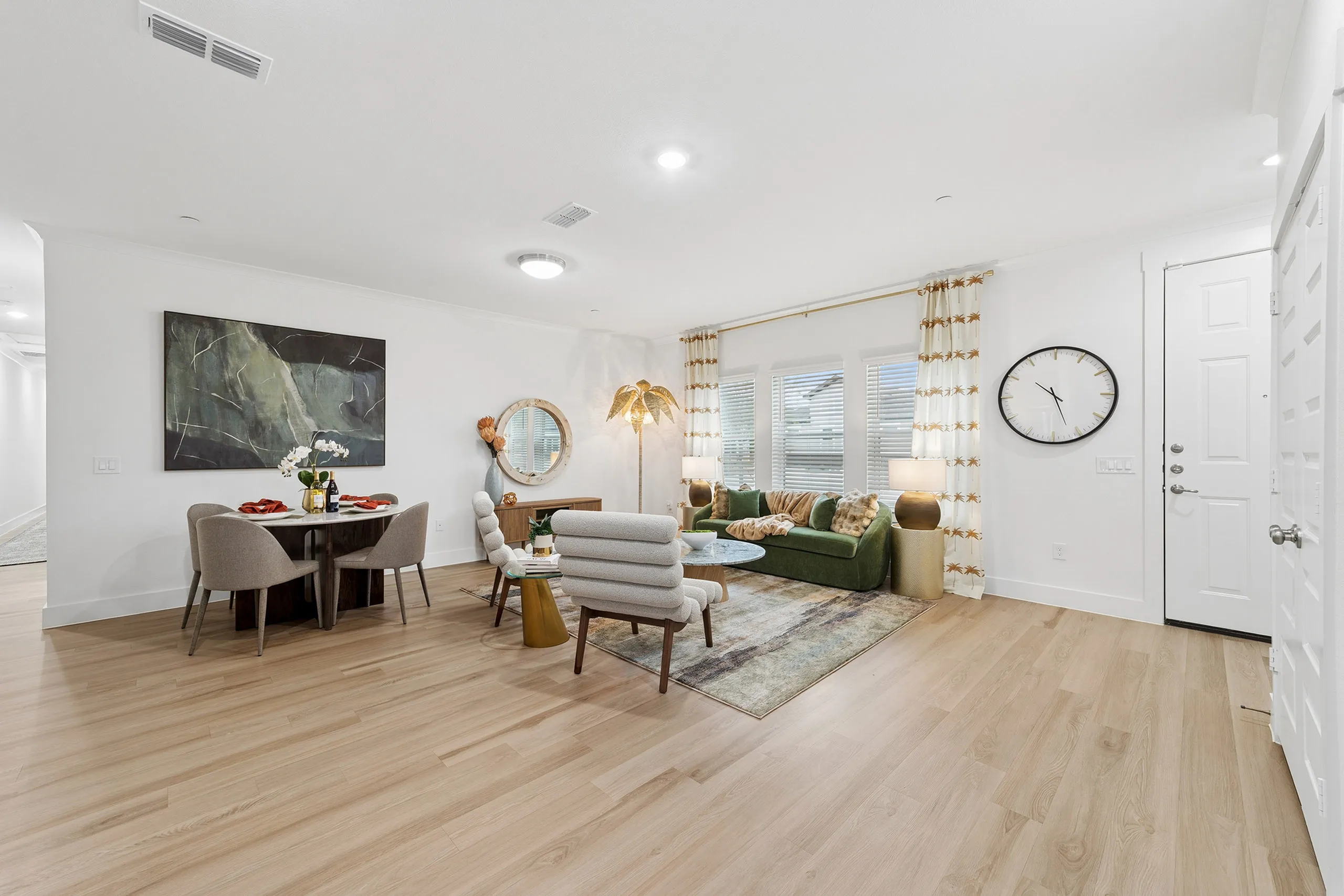 Contemporary open living area featuring a chic dining space, plush green sofa, and stylish decor with ample natural light.