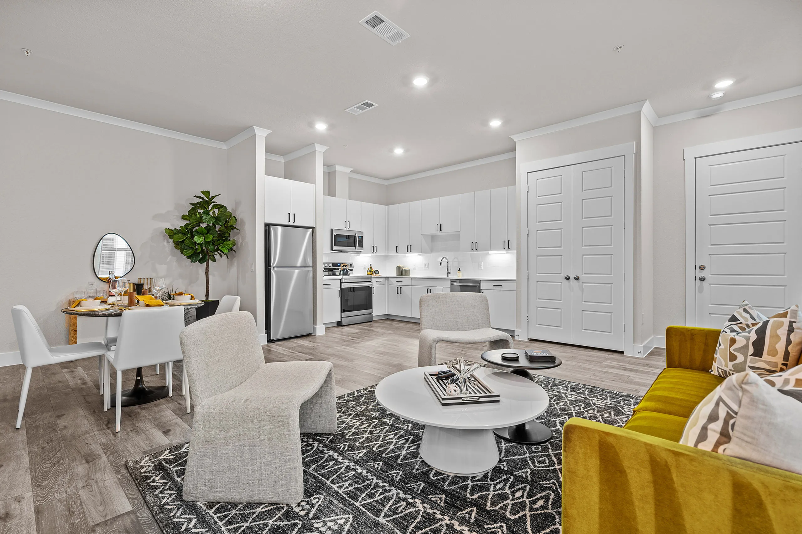 Chic open-concept living space featuring a modern kitchen with sleek white cabinets, stylish dining area, and cozy seating with vibrant accents.