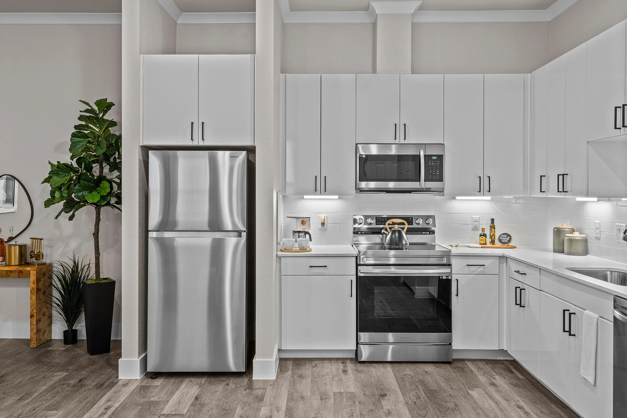 Modern kitchen with sleek stainless steel appliances, bright white cabinetry, and stylish hardwood flooring.