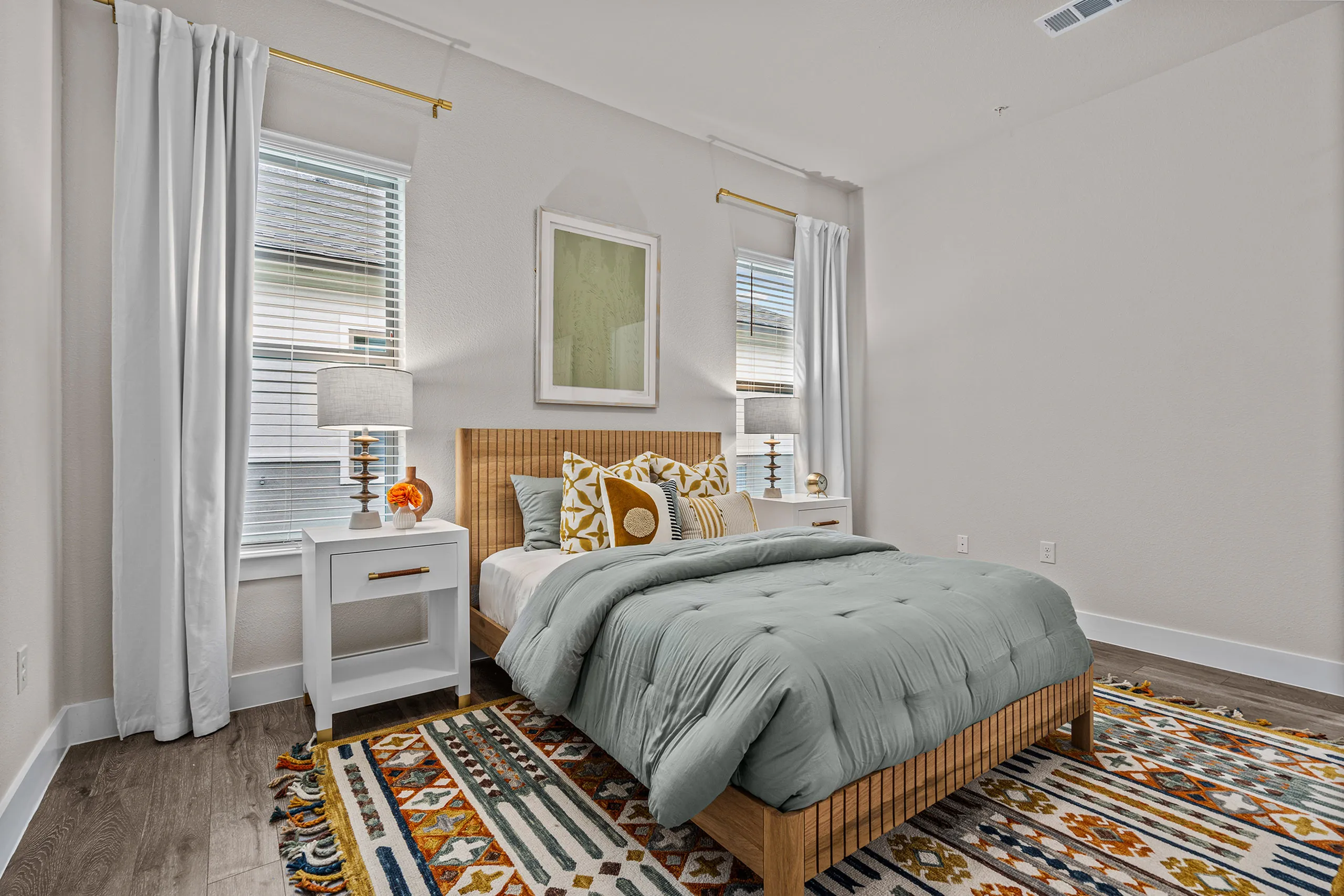 Bright and inviting bedroom featuring stylish decor, large windows with elegant drapery, cozy bedding, and modern furnishings.