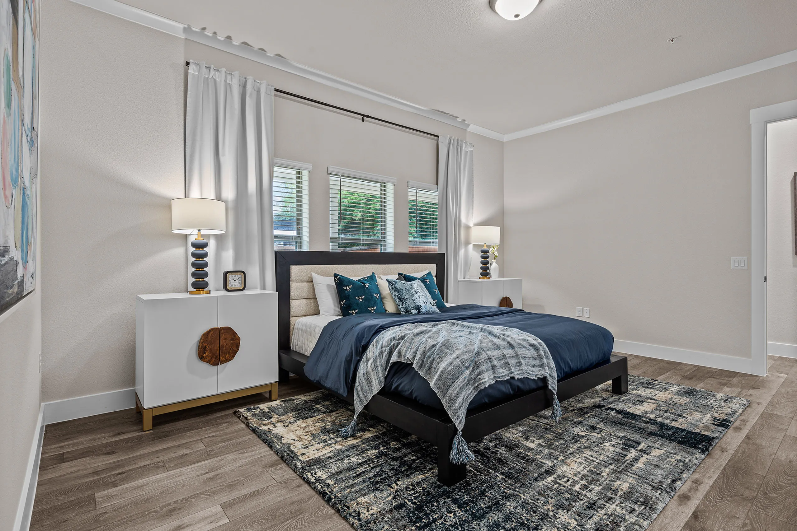 Elegant bedroom with chic decor, featuring a plush bed, stylish lamps on modern nightstands, and natural light flowing through large windows.