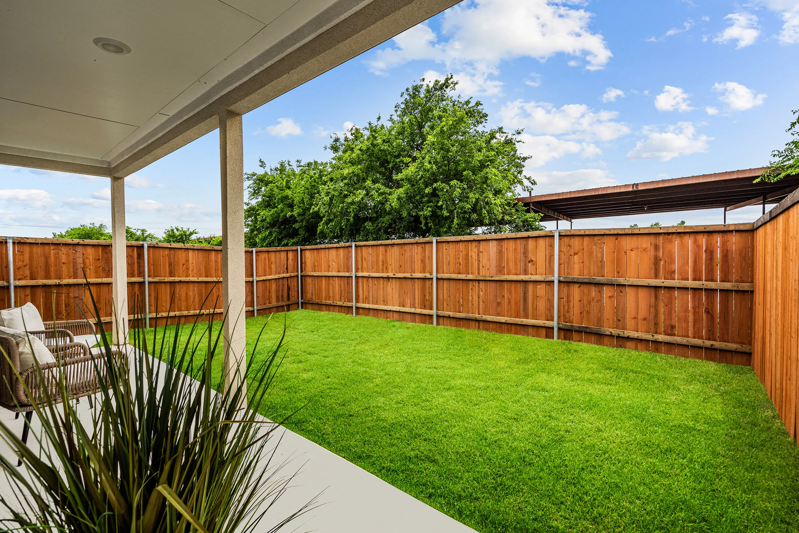 Inviting backyard with lush green lawn, wooden fencing, and cozy patio seating, perfect for relaxation and outdoor enjoyment.