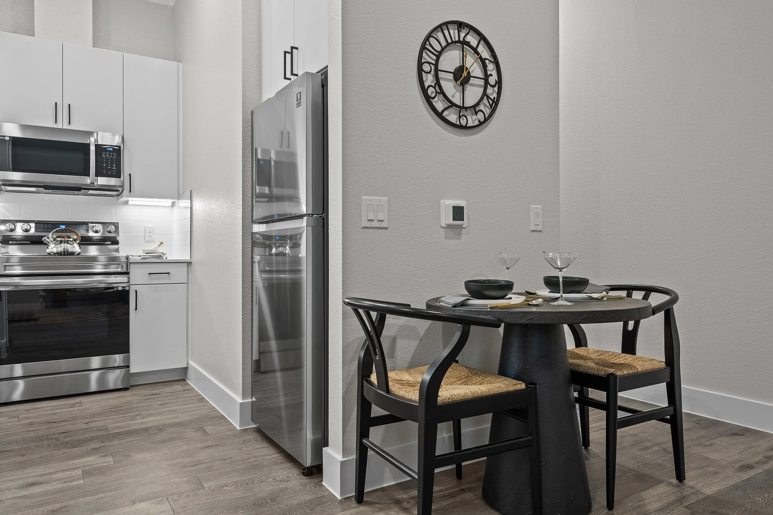 Modern kitchen with stainless steel appliances and cozy dining area, featuring a round table set for two.