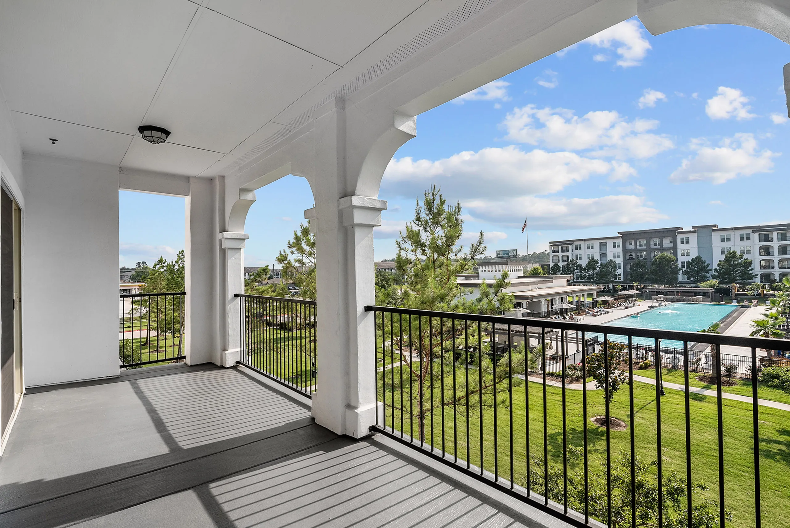 Charming balcony view showcasing a lush green landscape and a stylish pool area, perfect for relaxation.