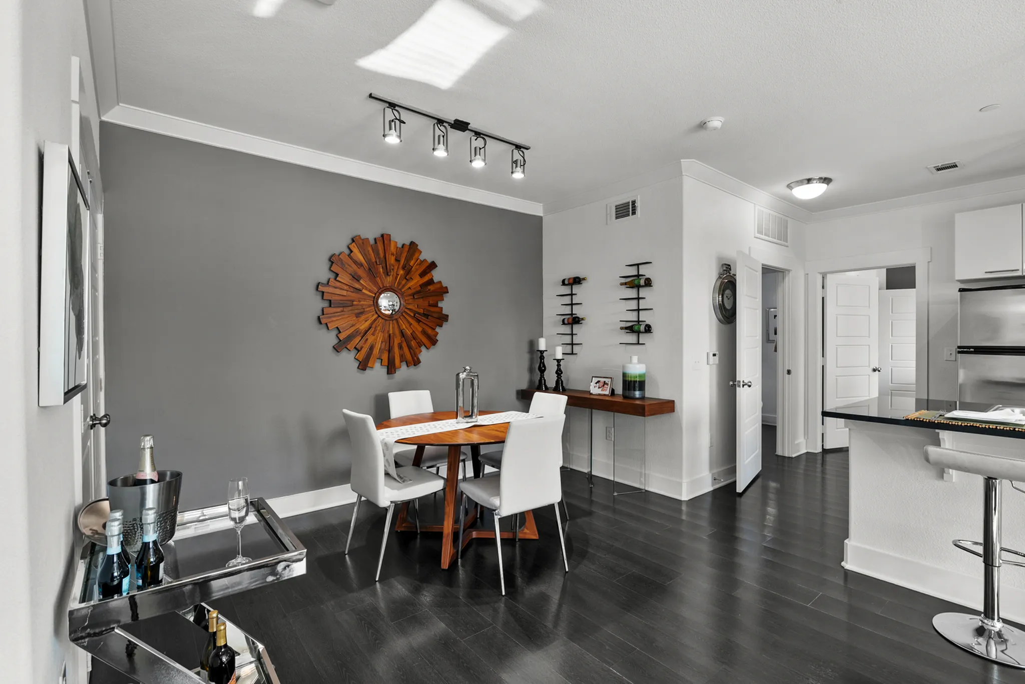 Modern dining area with sleek dark flooring, stylish round wooden table, and contemporary decor, perfect for entertaining guests.