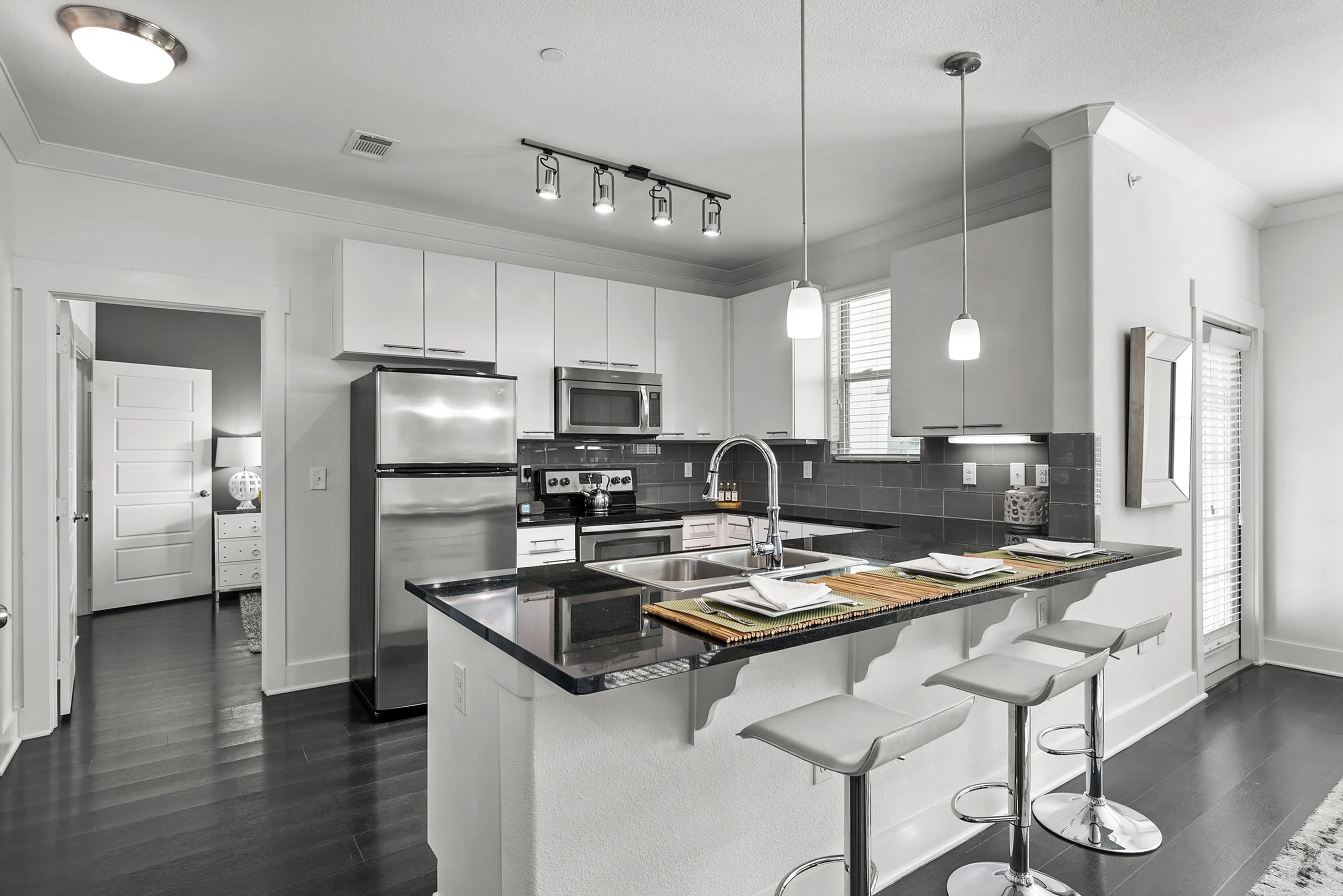 Sleek modern kitchen with white cabinetry, stainless steel appliances, and chic pendant lighting over a stylish breakfast bar.