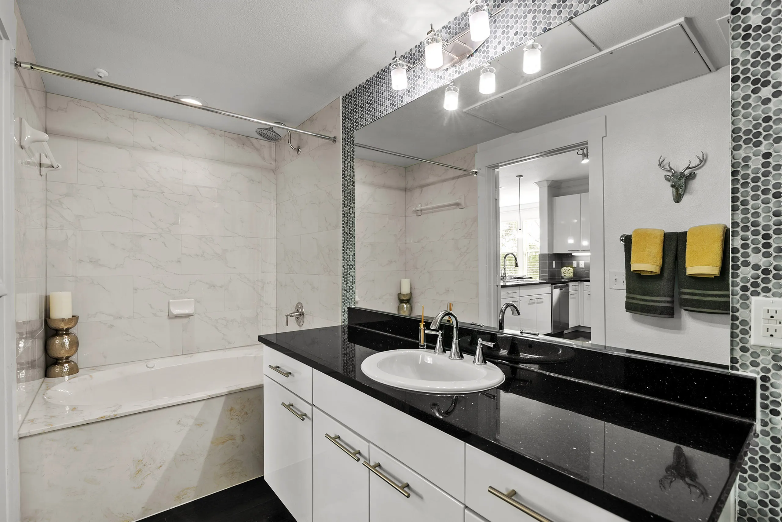 Elegant modern bathroom with marble tub, sleek black countertop, and stylish lighting.