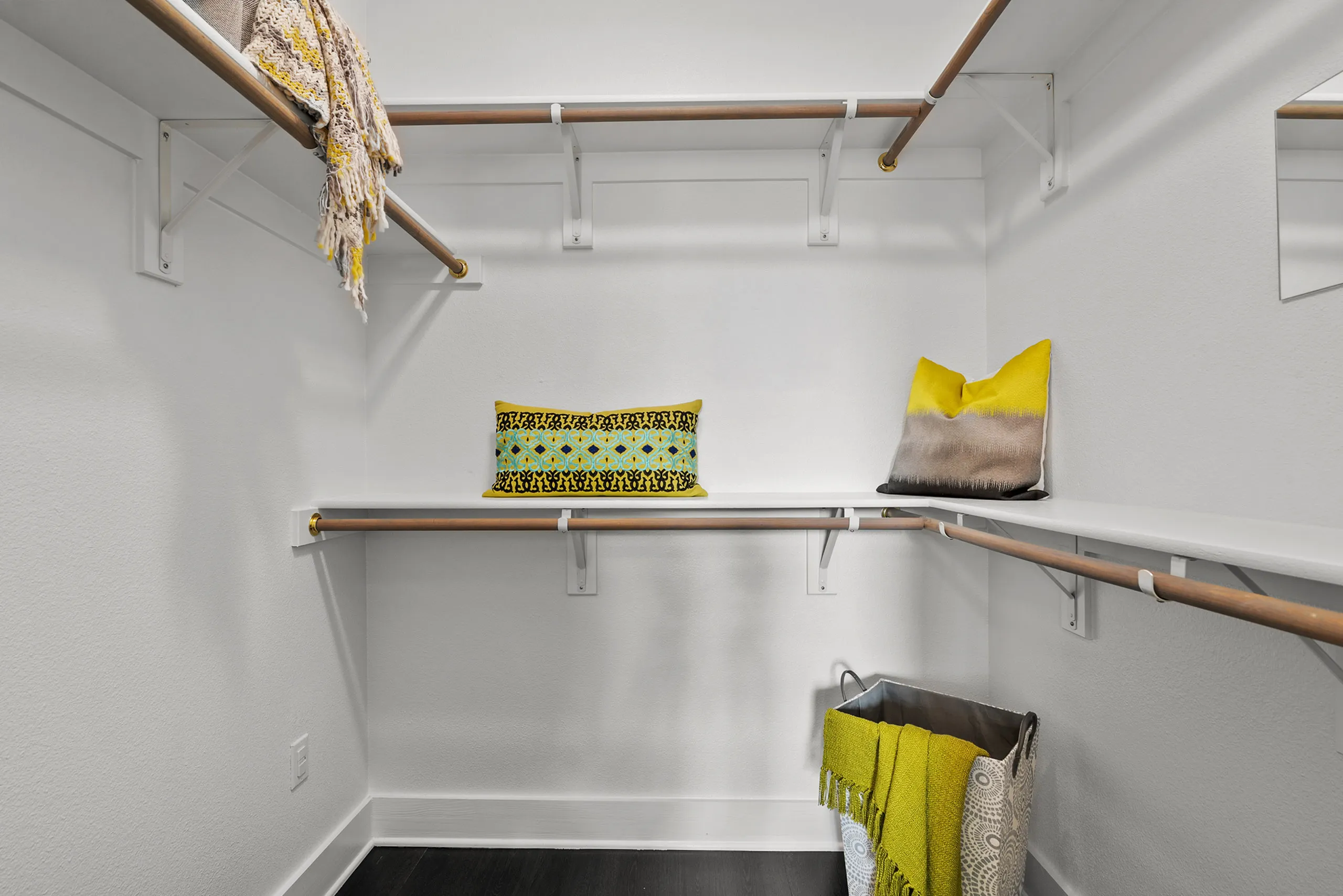 Spacious walk-in closet with elegant shelving, decorative pillows, and vibrant accents in a modern apartment.