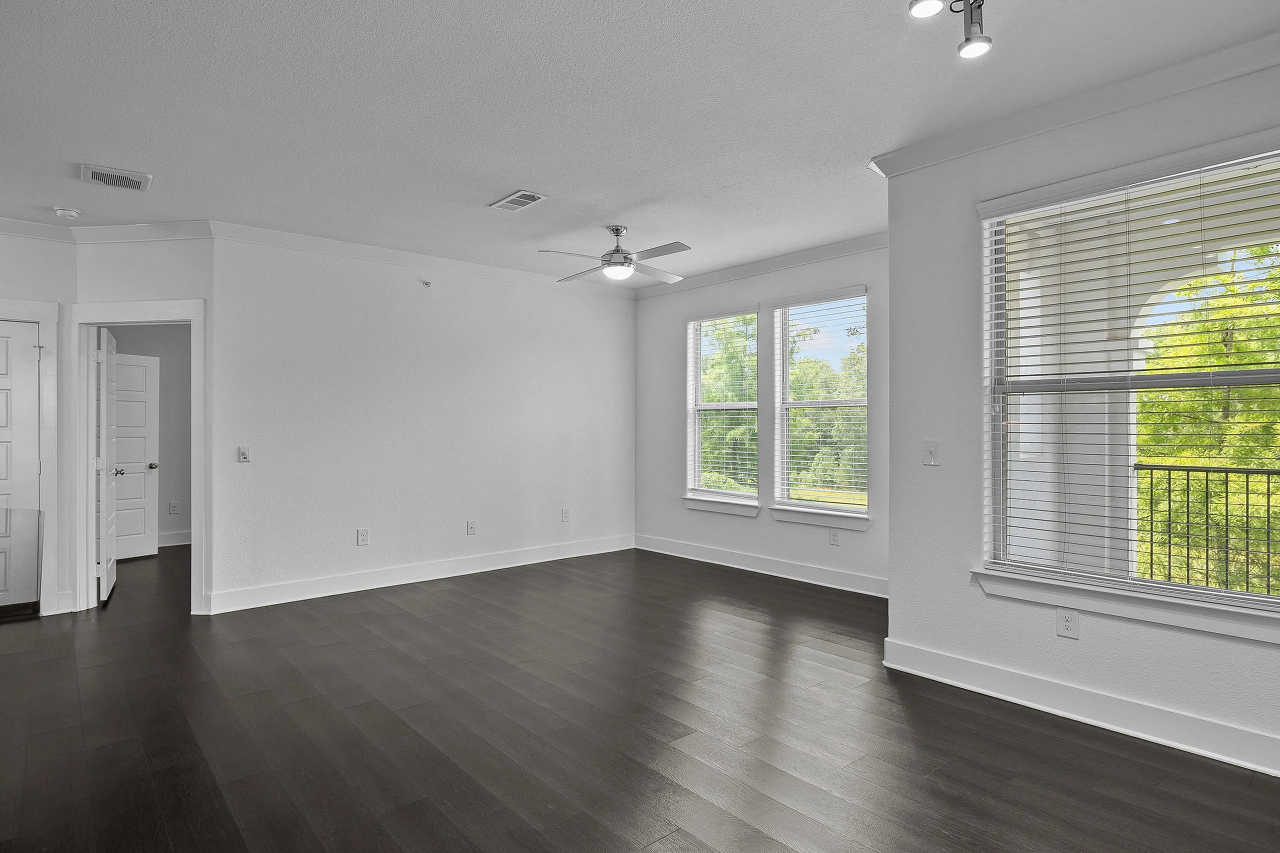Bright, modern living space with sleek dark wood flooring and large windows offering scenic views.