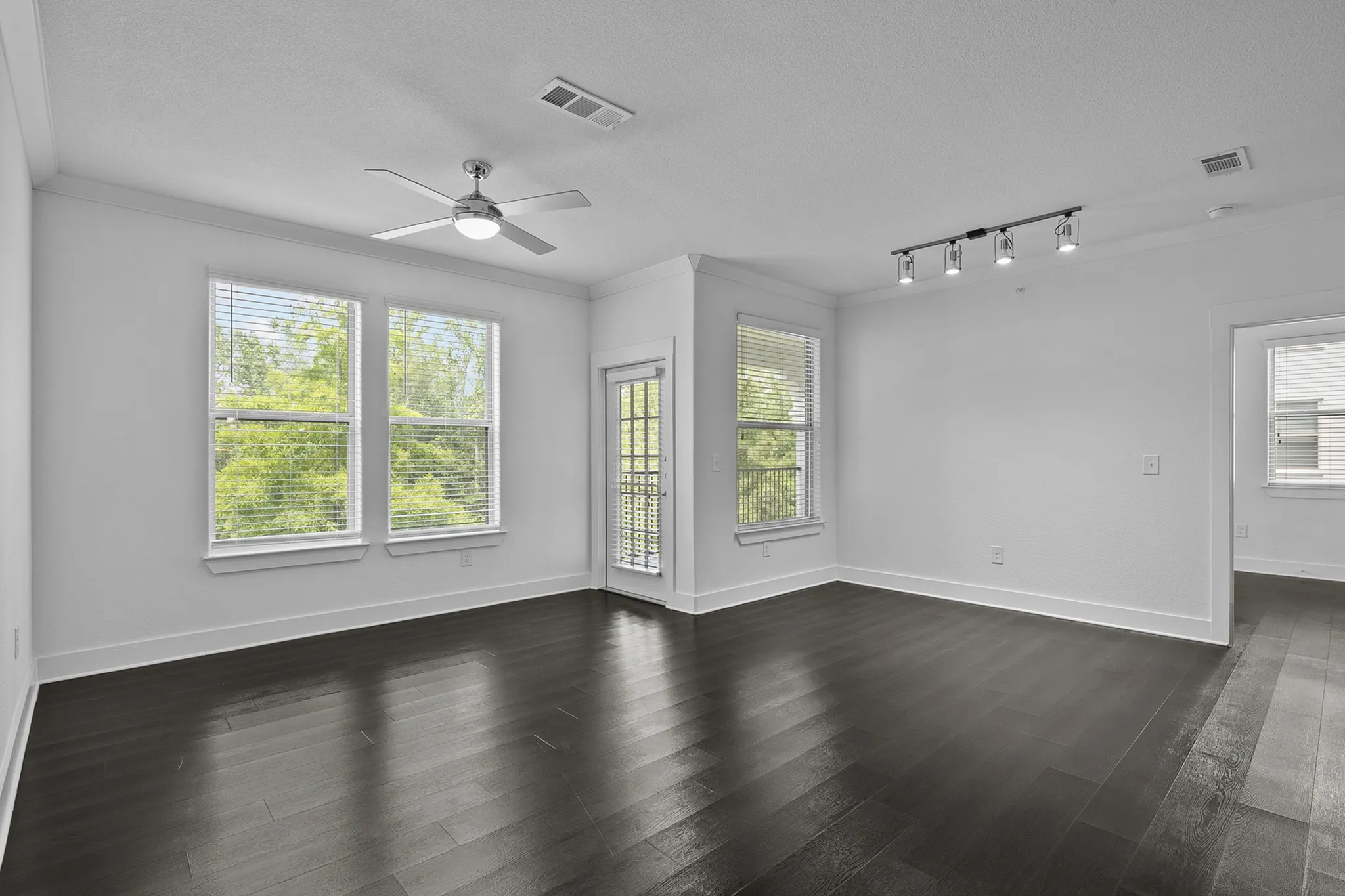 Bright and airy living room with sleek dark hardwood floors, large windows, and modern lighting, perfect for contemporary living.