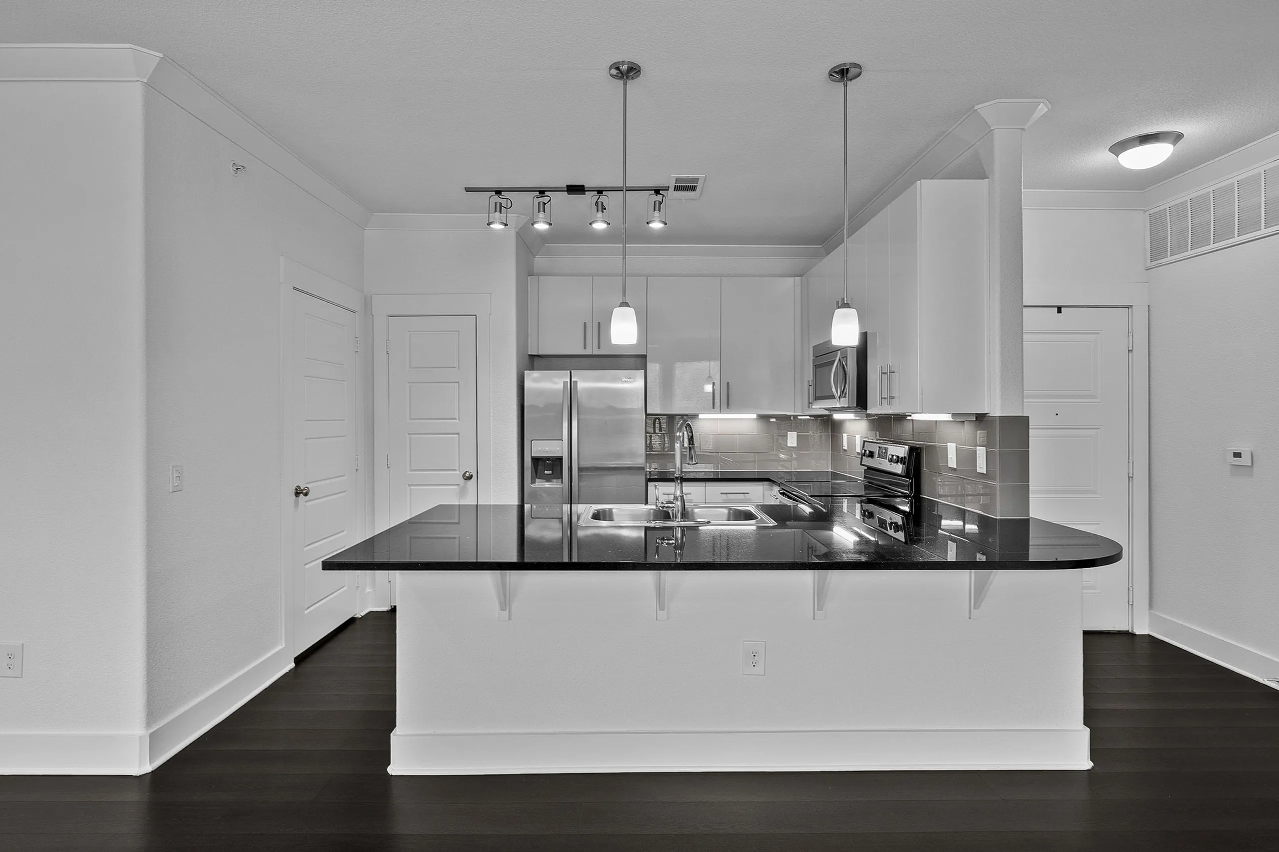 Modern kitchen with sleek black countertops, stainless steel appliances, and elegant pendant lighting.