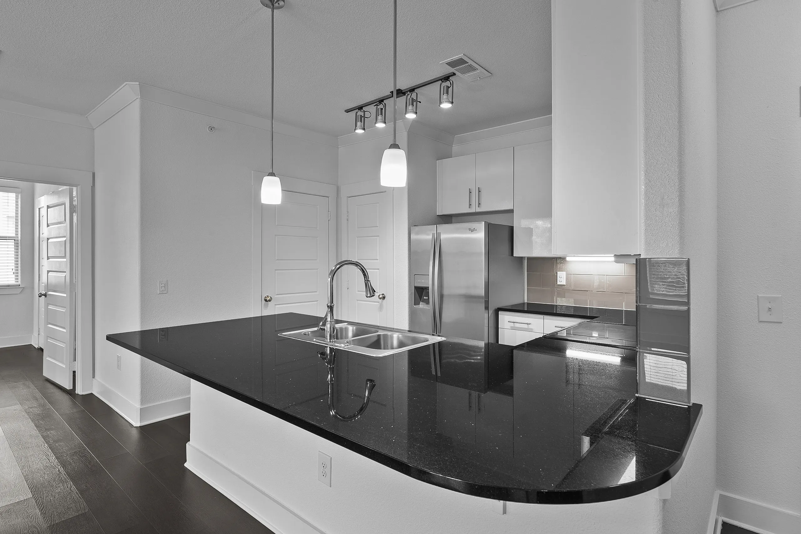 Modern kitchen with sleek black granite countertops, stainless steel appliances, and elegant pendant lighting.