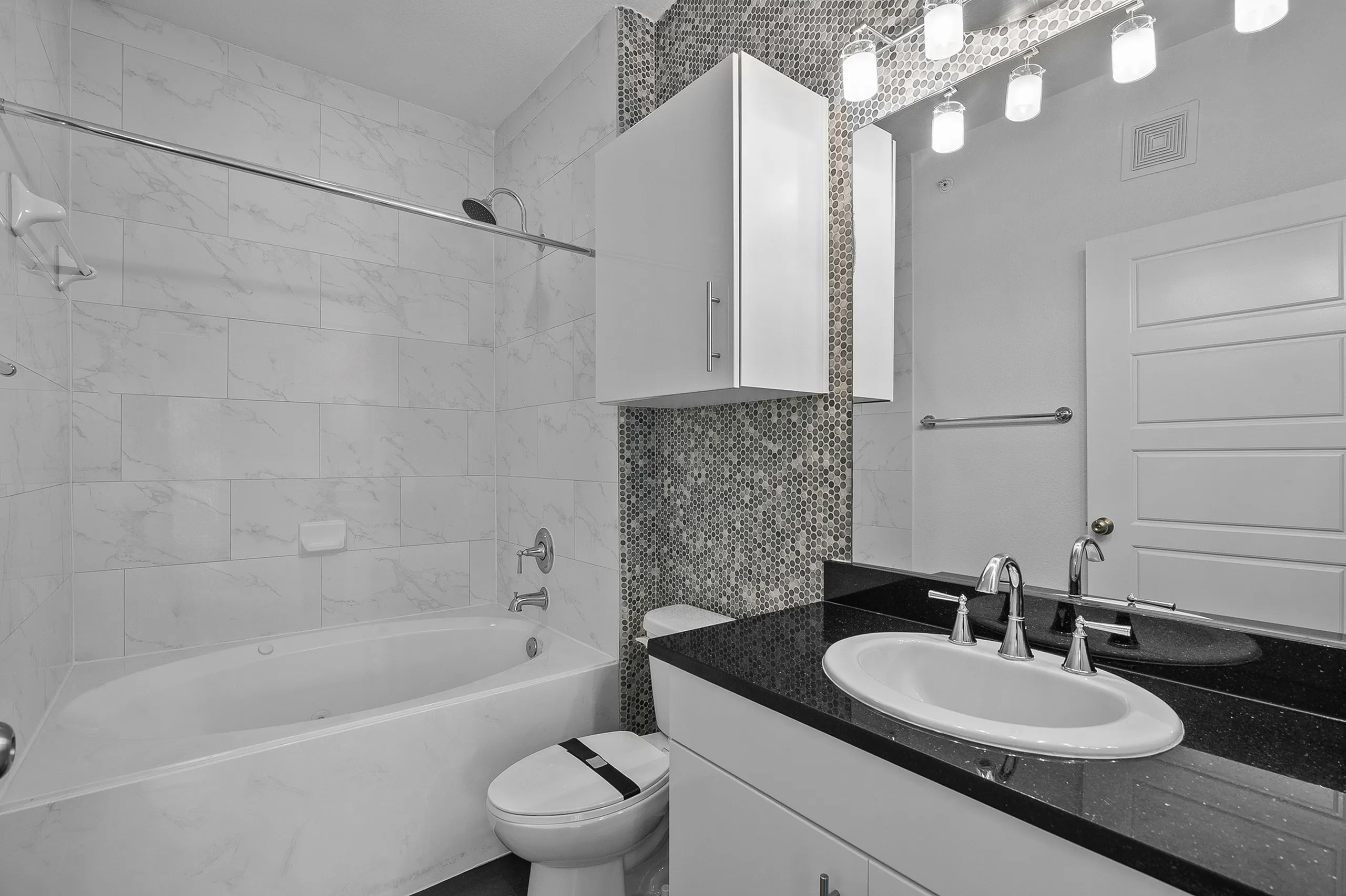 Modern bathroom featuring elegant tile walls, a sleek vanity with black countertop, and a chic shower-tub combo.