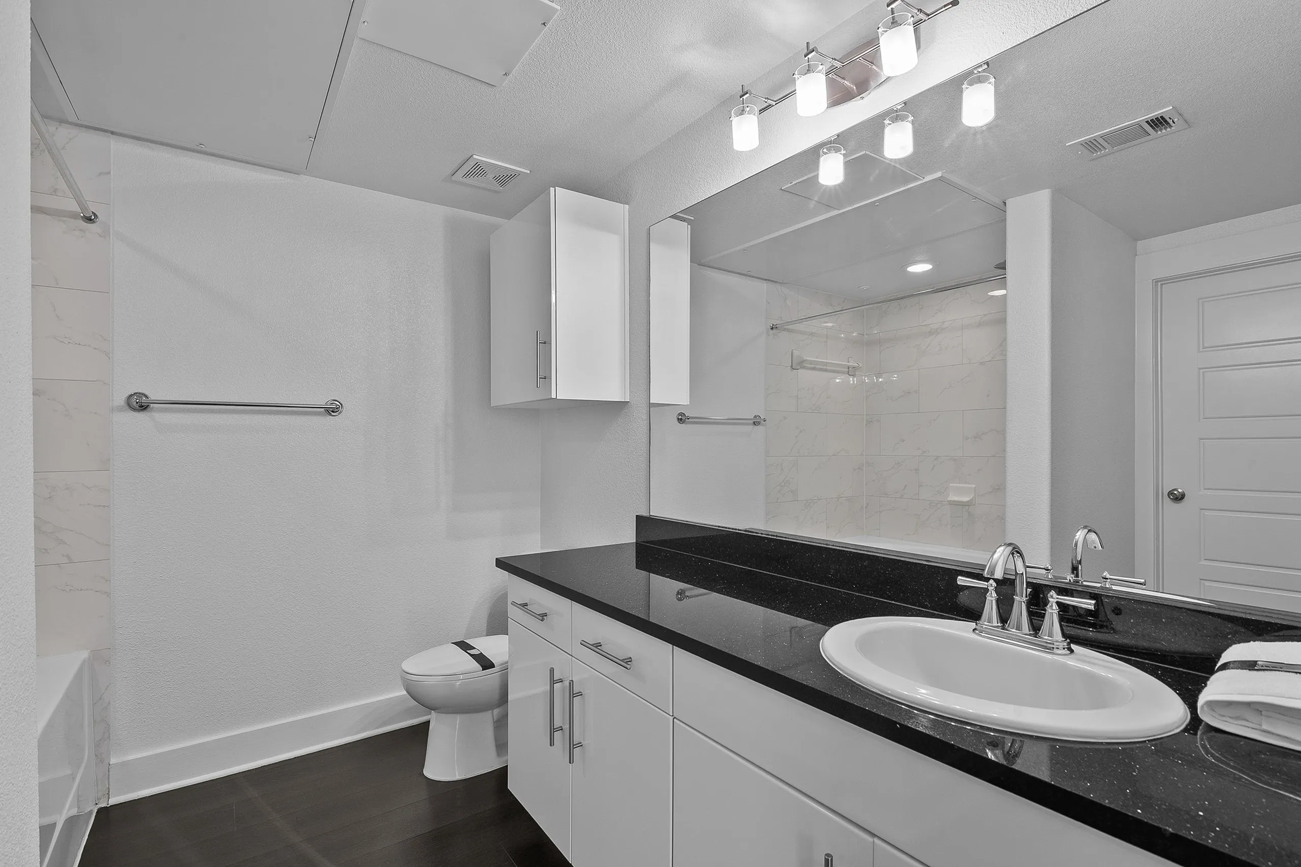 Elegant bathroom featuring a sleek black countertop, modern lighting, and spacious cabinets, offering a luxurious and functional design.