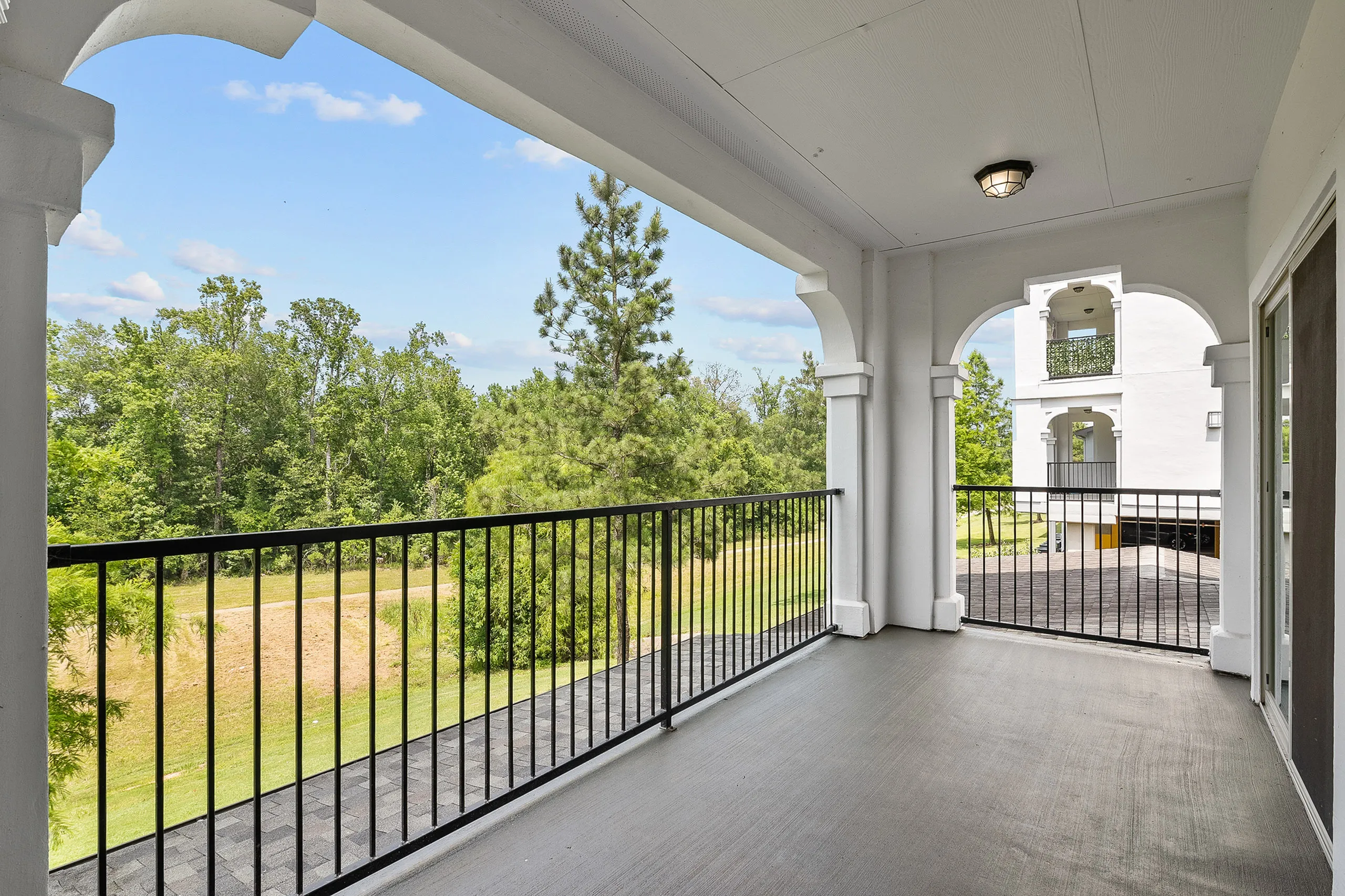 Inviting balcony view showcasing serene greenery, perfect for relaxation with elegant arch details.
