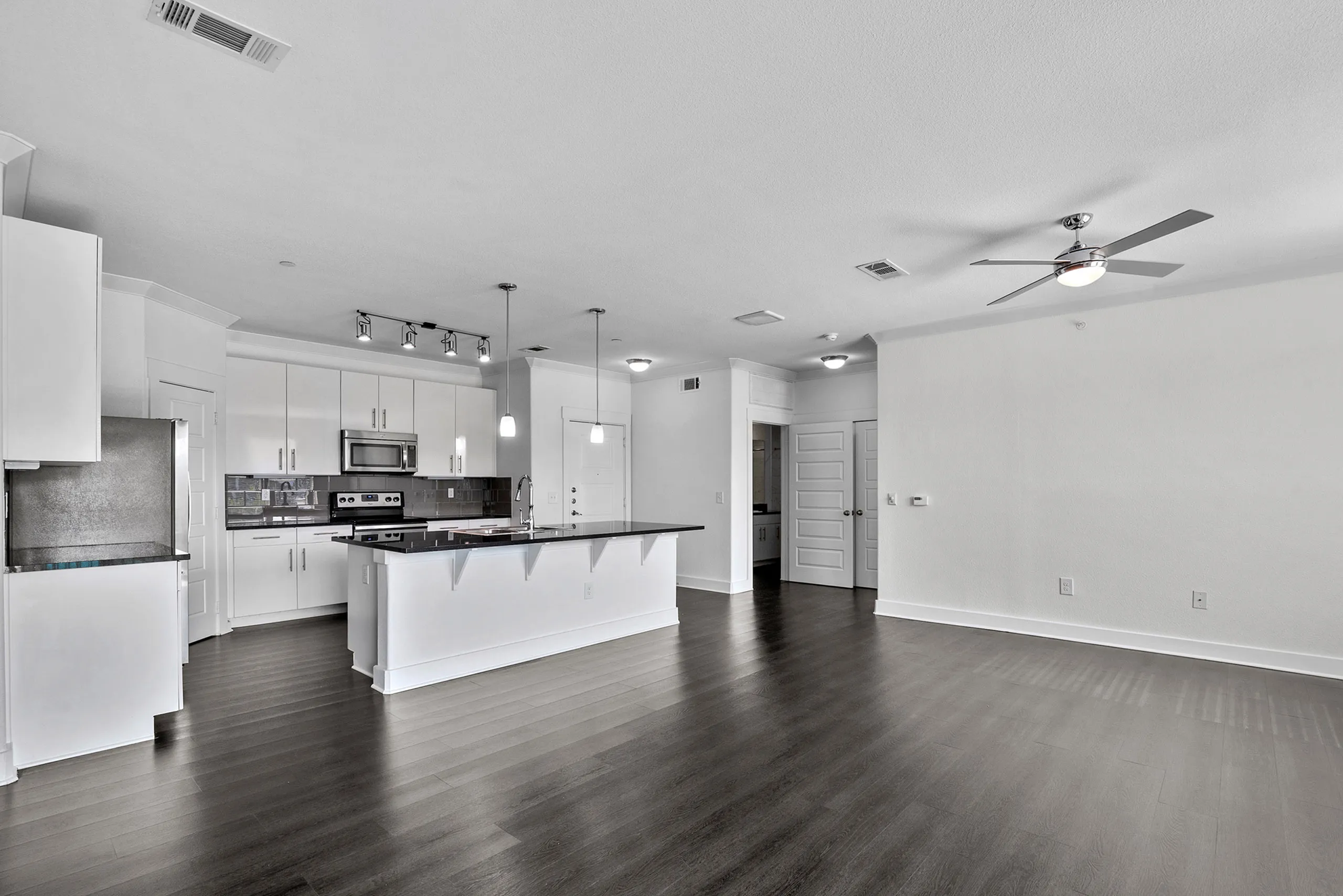 Sleek open-concept living area showcasing a modern kitchen with white cabinetry, stainless steel appliances, and elegant lighting.
